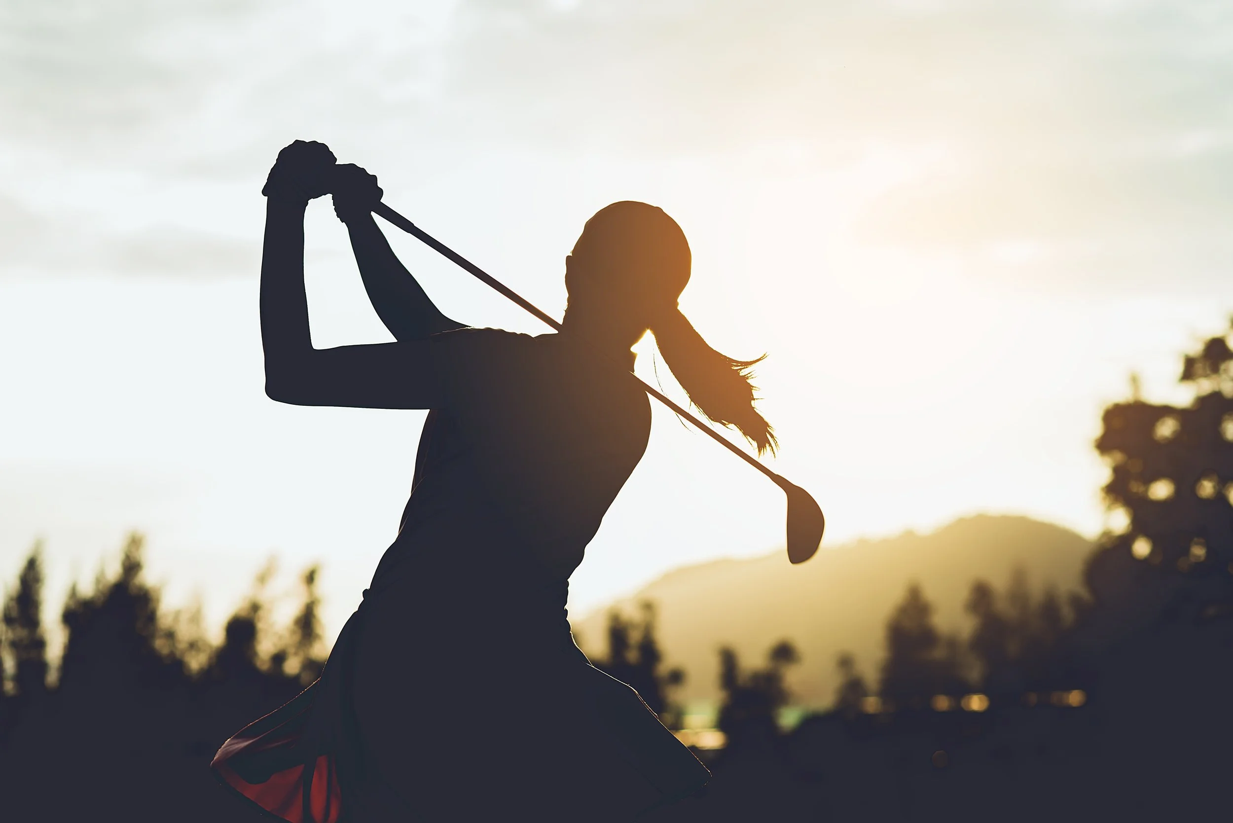 Silhouette of a woman swinging a golf club