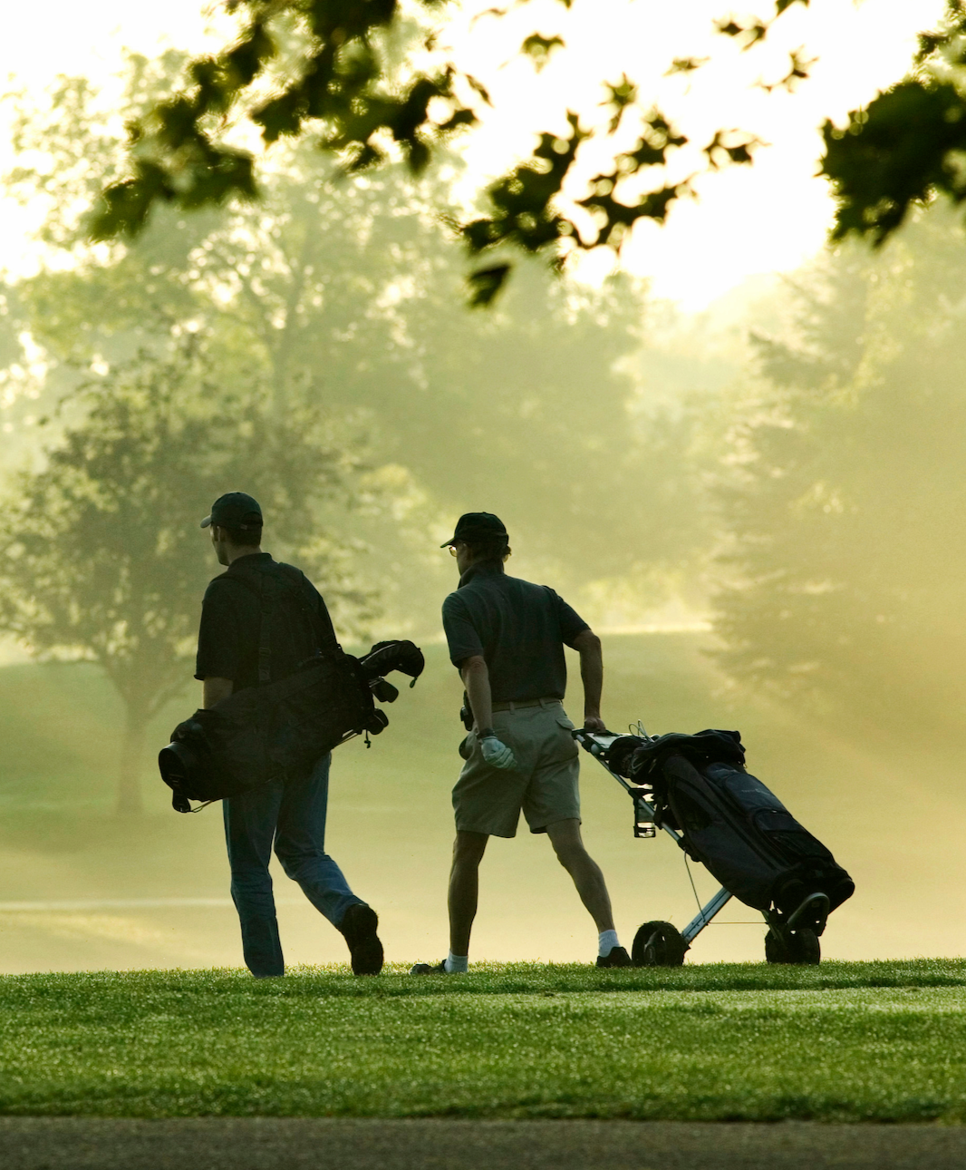 Two guys carrying golf equipment