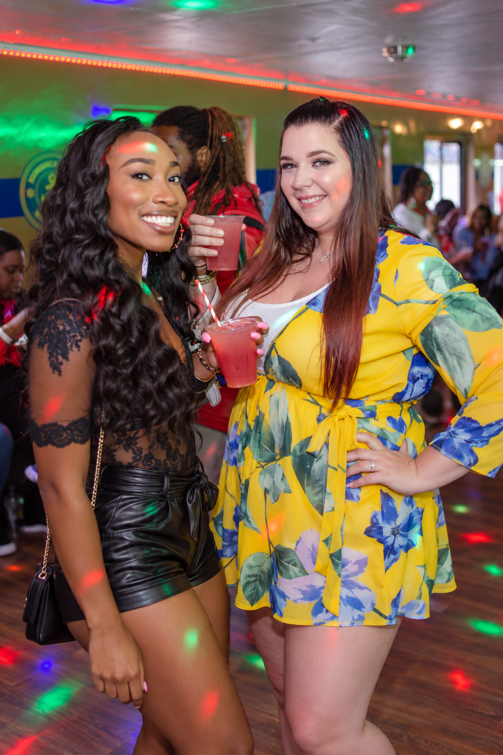 Two guests smiling with drinks at a boat party.