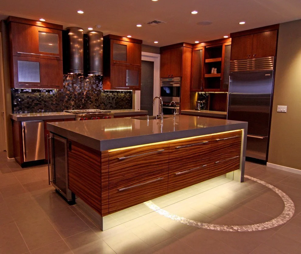 Finished custom kitchen with island lighting, dark wood cabinetry, and stainless steel appliances