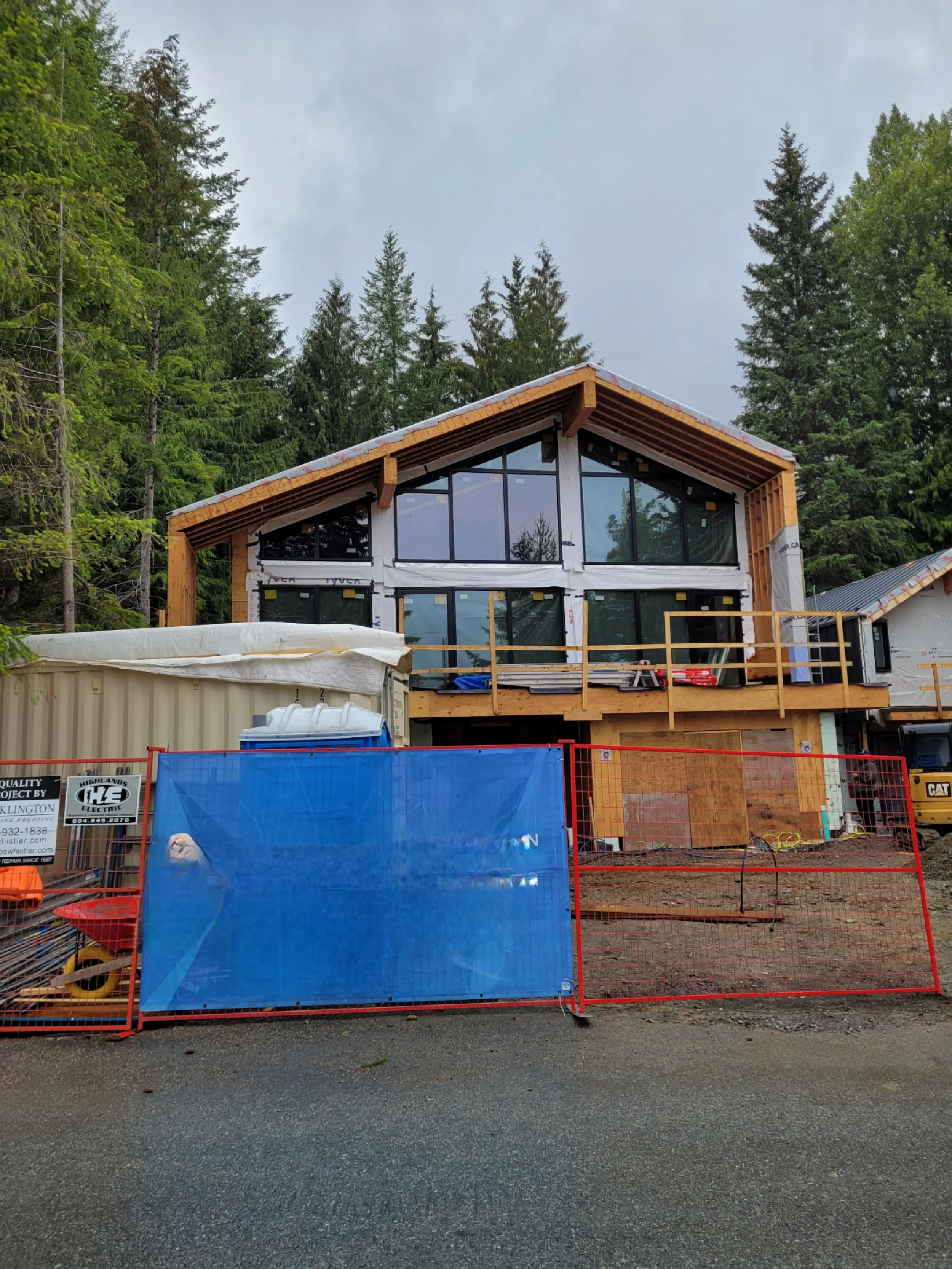 Timber-frame home under construction with site hoarding before electrical completion
