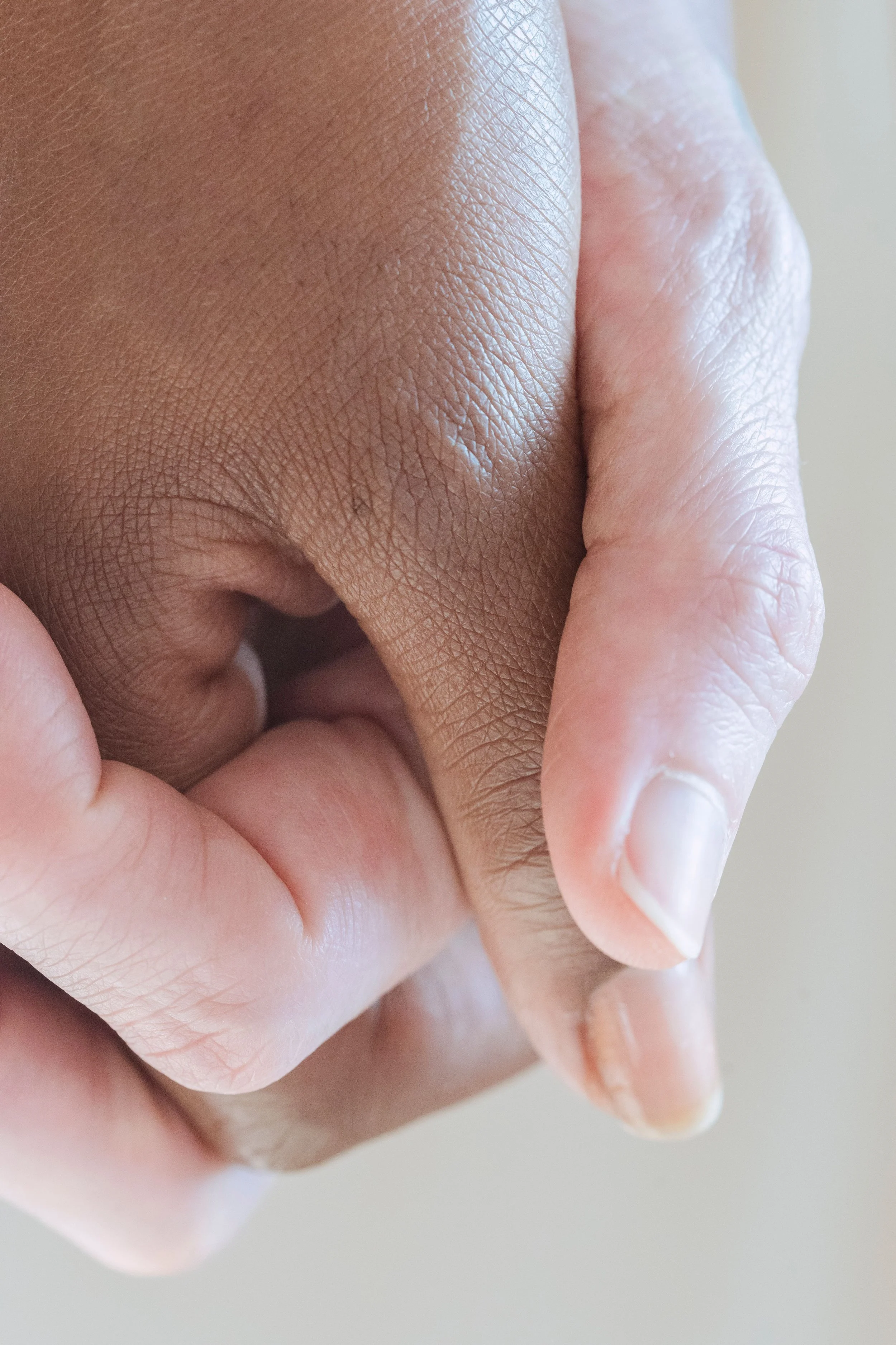 Close-up of two hands with fingers interlocked.