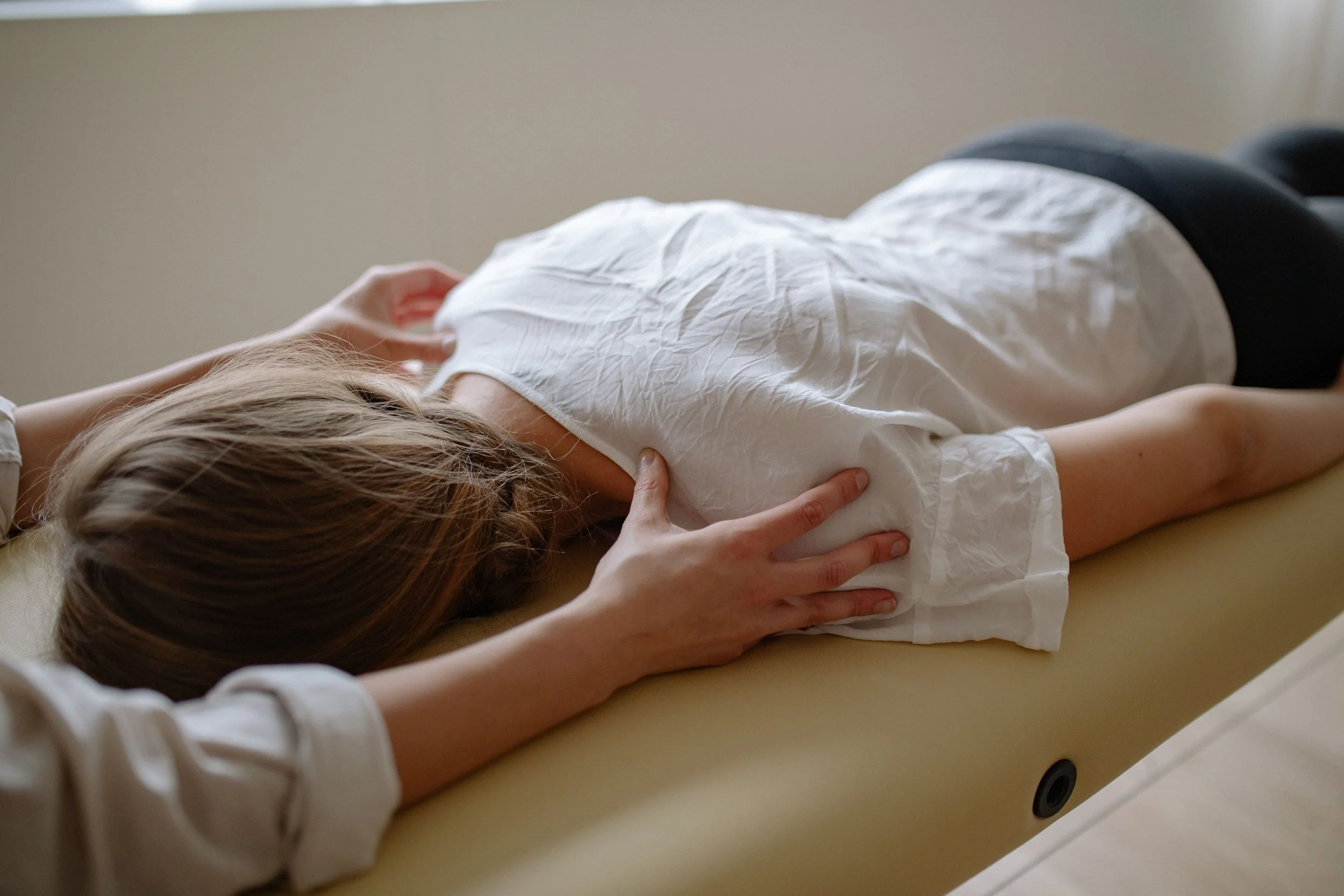 Person lying on a table receiving osteopathic manipulative medicine treatment.