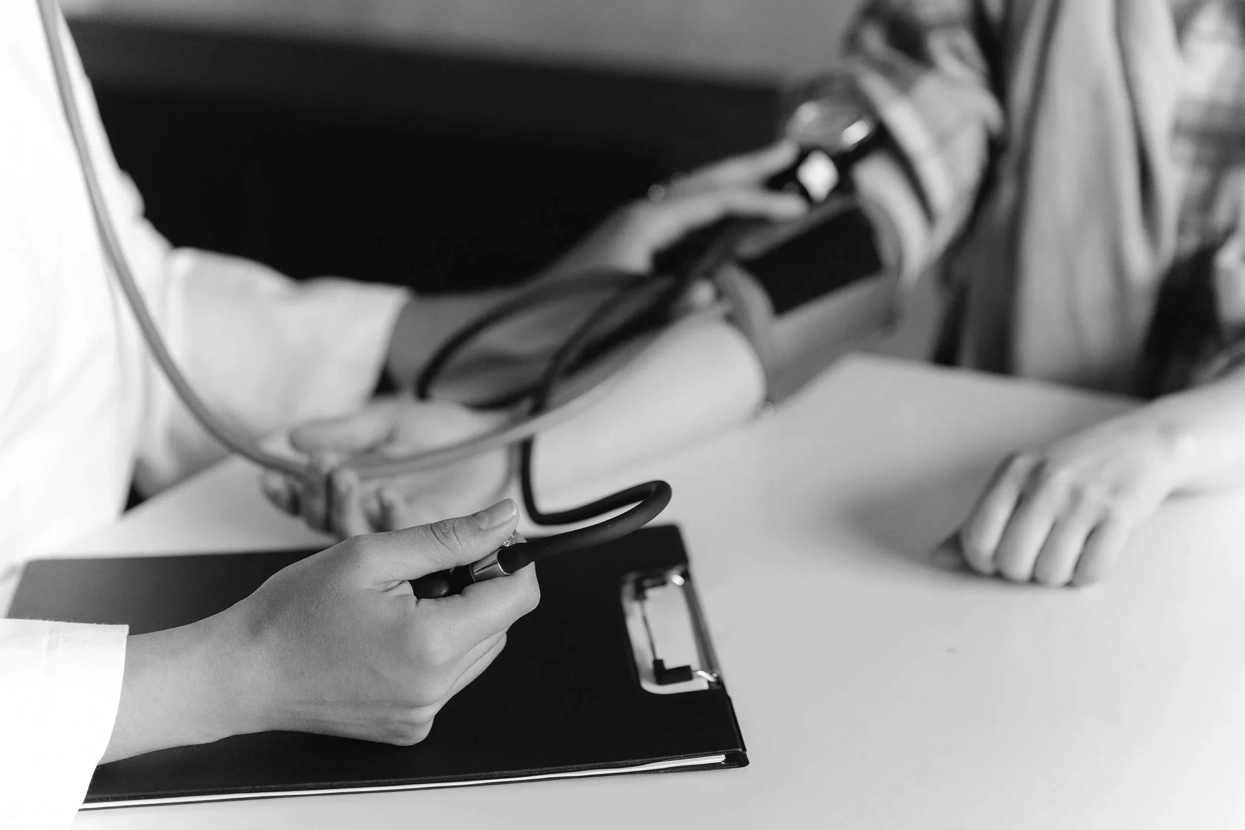 A person holding a pen near a notebook, with wires and electronic components on a table.
