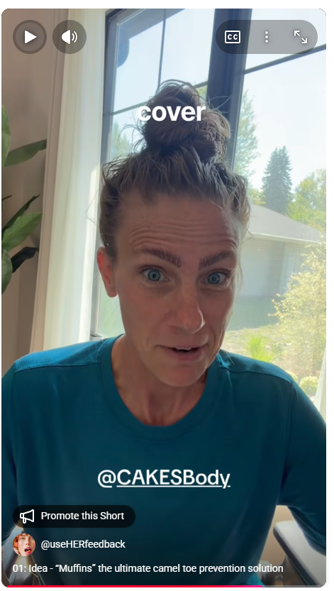 A woman with her hair in a messy bun sitting near a window, wearing a blue shirt, with outdoor trees visible through the window.