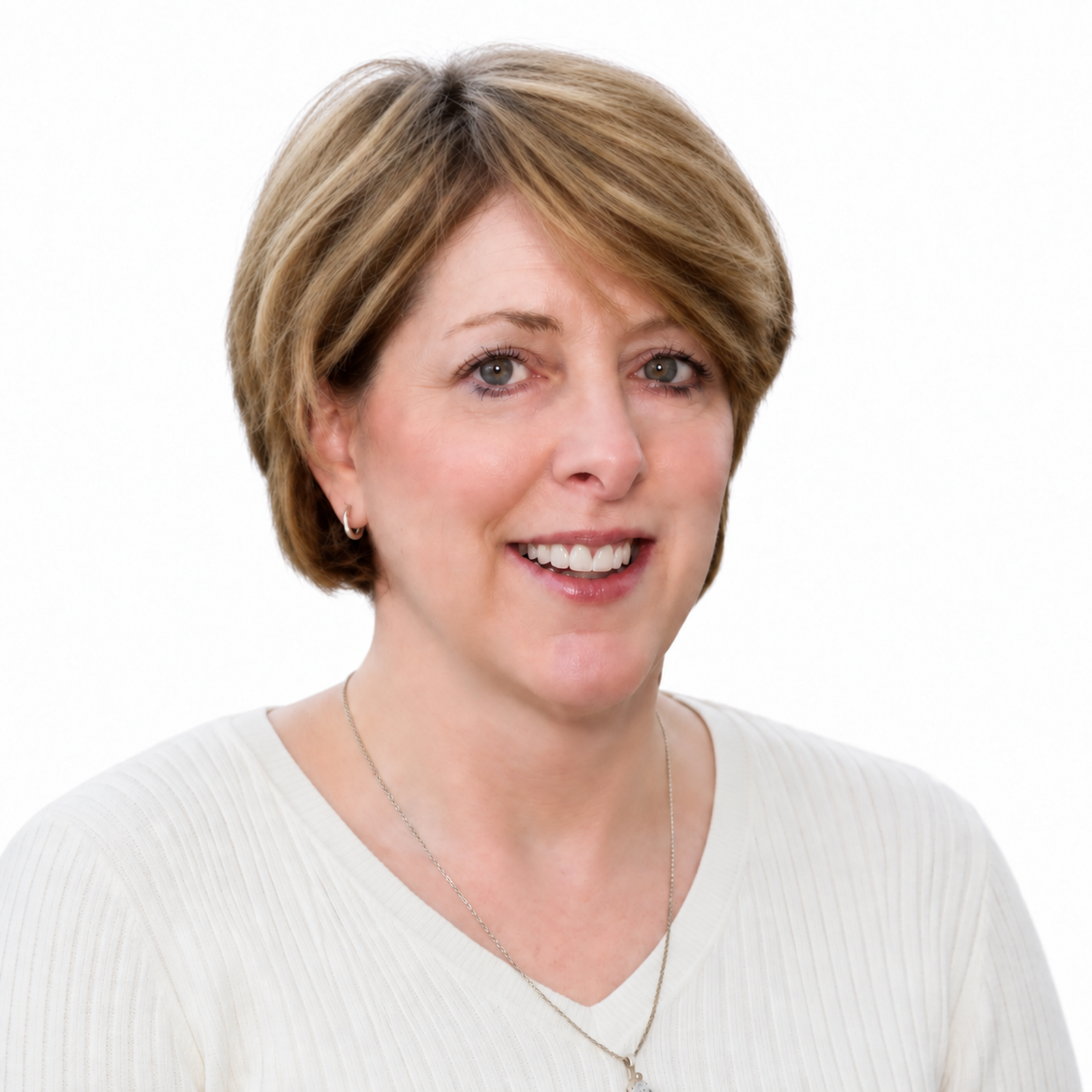 A smiling woman with short, light brown hair and blue eyes, wearing a white top and silver jewelry, against a white background.