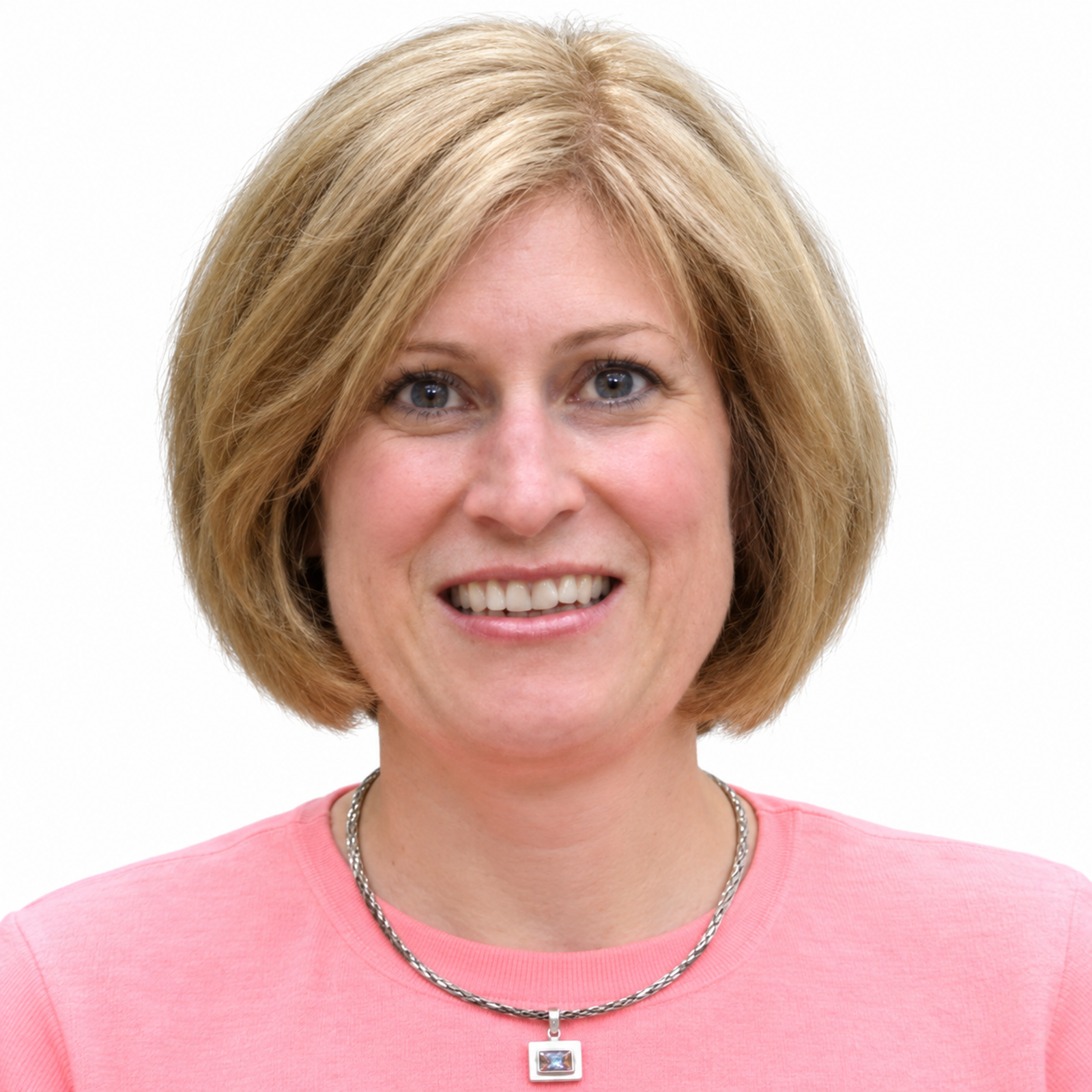 Close-up of a smiling middle-aged woman with blonde hair wearing a pink shirt and a silver chain necklace.