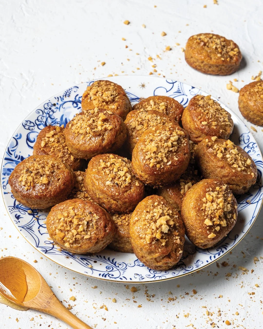 Plate of freshly baked falafel balls topped with crushed nuts, served on a decorative blue and white porcelain plate.