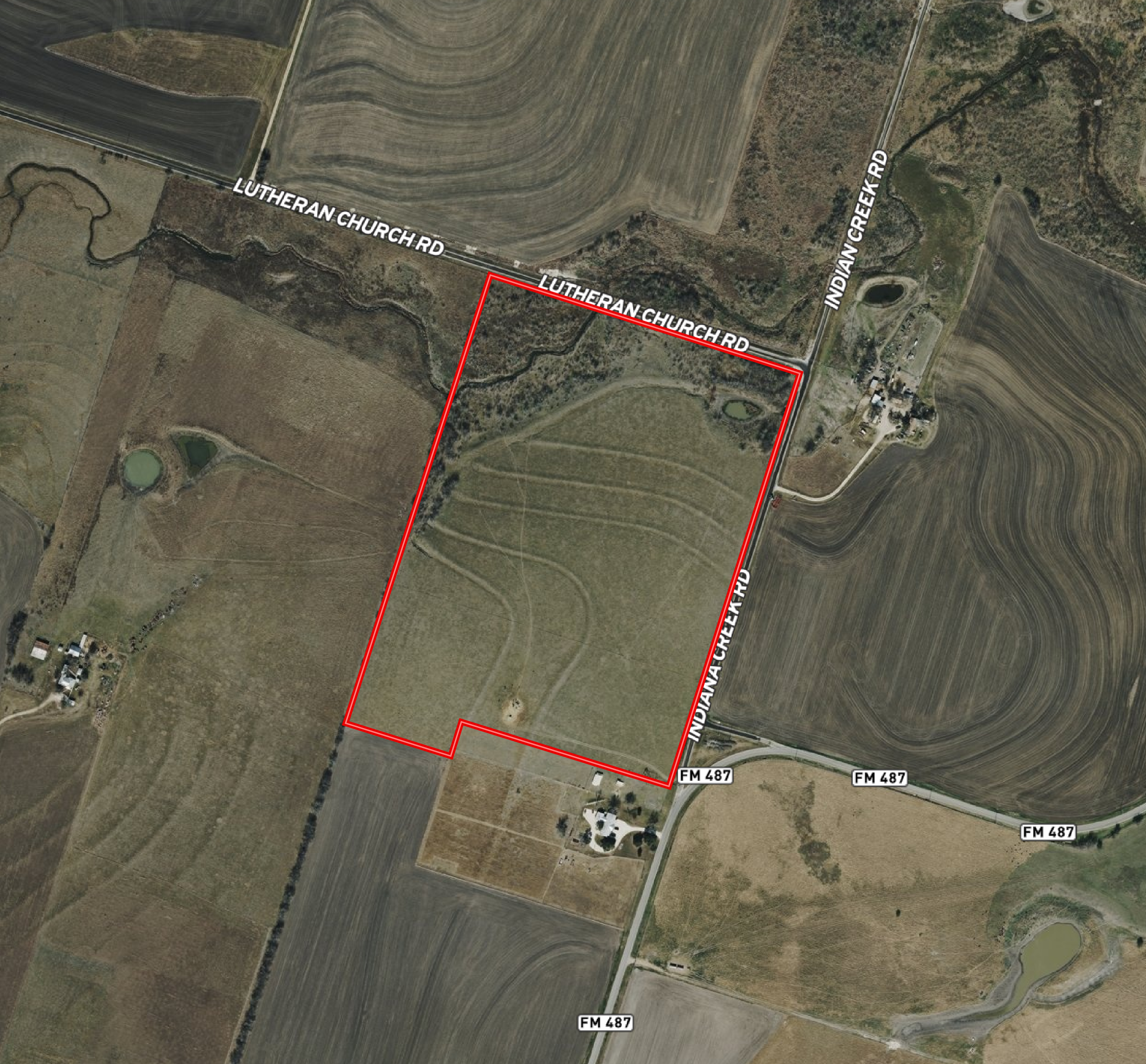 Aerial view of farmland with roads, fields, and small ponds, with a red outline marking a property boundary along Lutheran Church Road and Indian Creek Road.