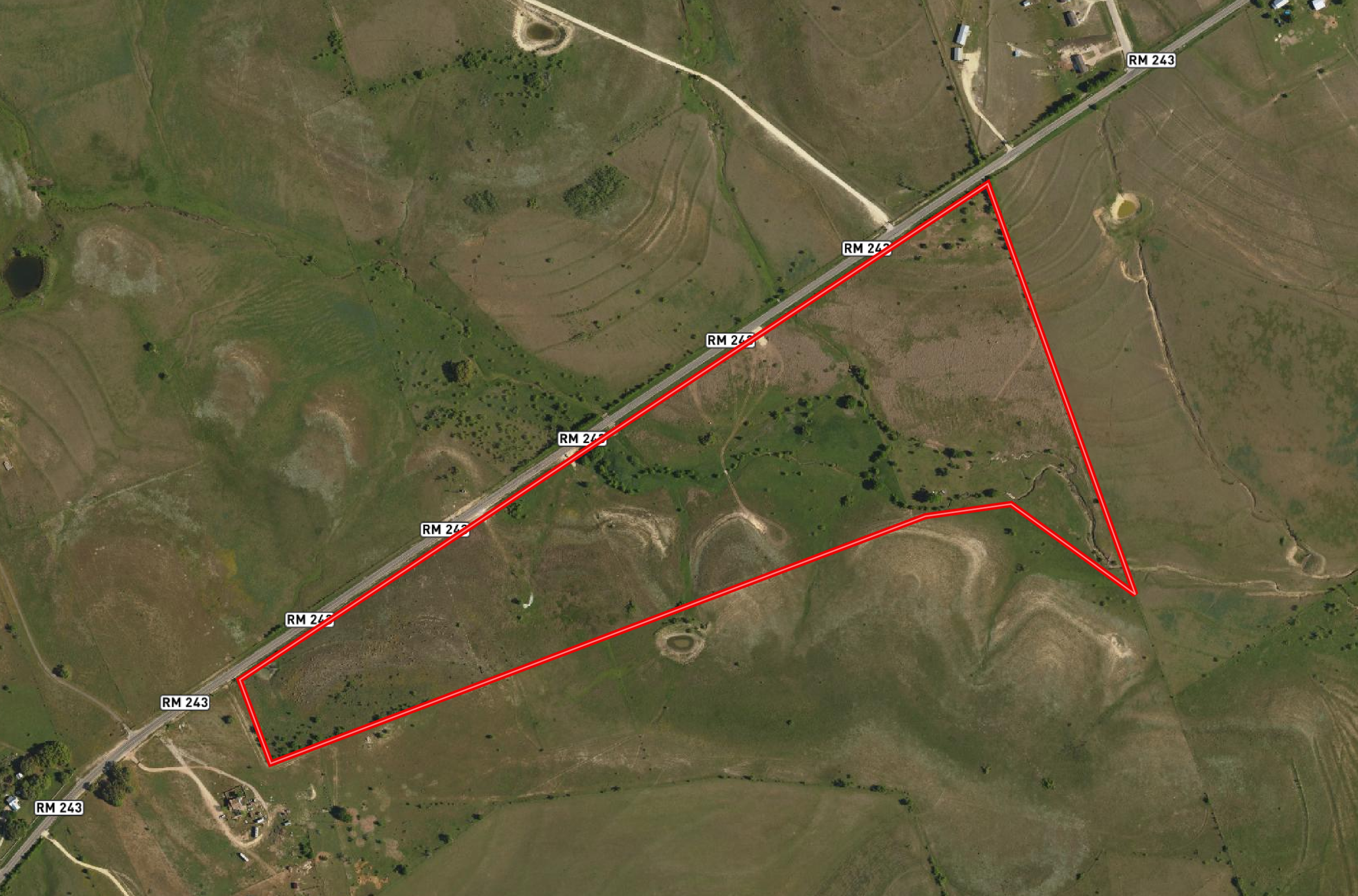 Satellite map showing a rural area with green fields, small ponds, and dirt roads. There are labels for roads RM 243, RM 242, and RM 247. A red boundary outline marks a specific property in the lower right section of the image.