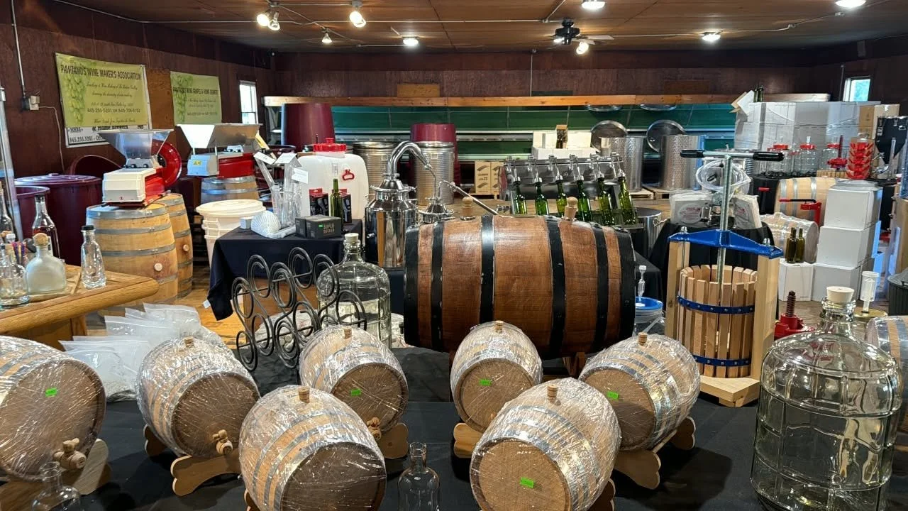 Wine-making equipment including barrels, glass bottles, and wine processing machines in a cellar or winery setting.