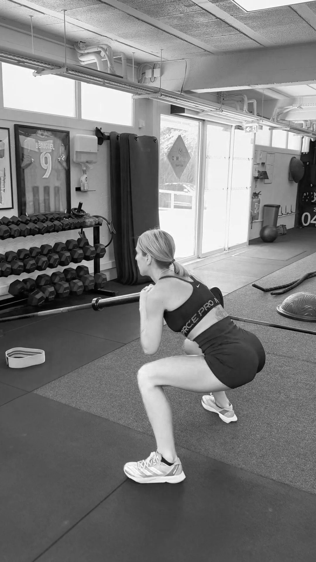 Une femme effectuant un squat avec un bâton dans une salle de sport