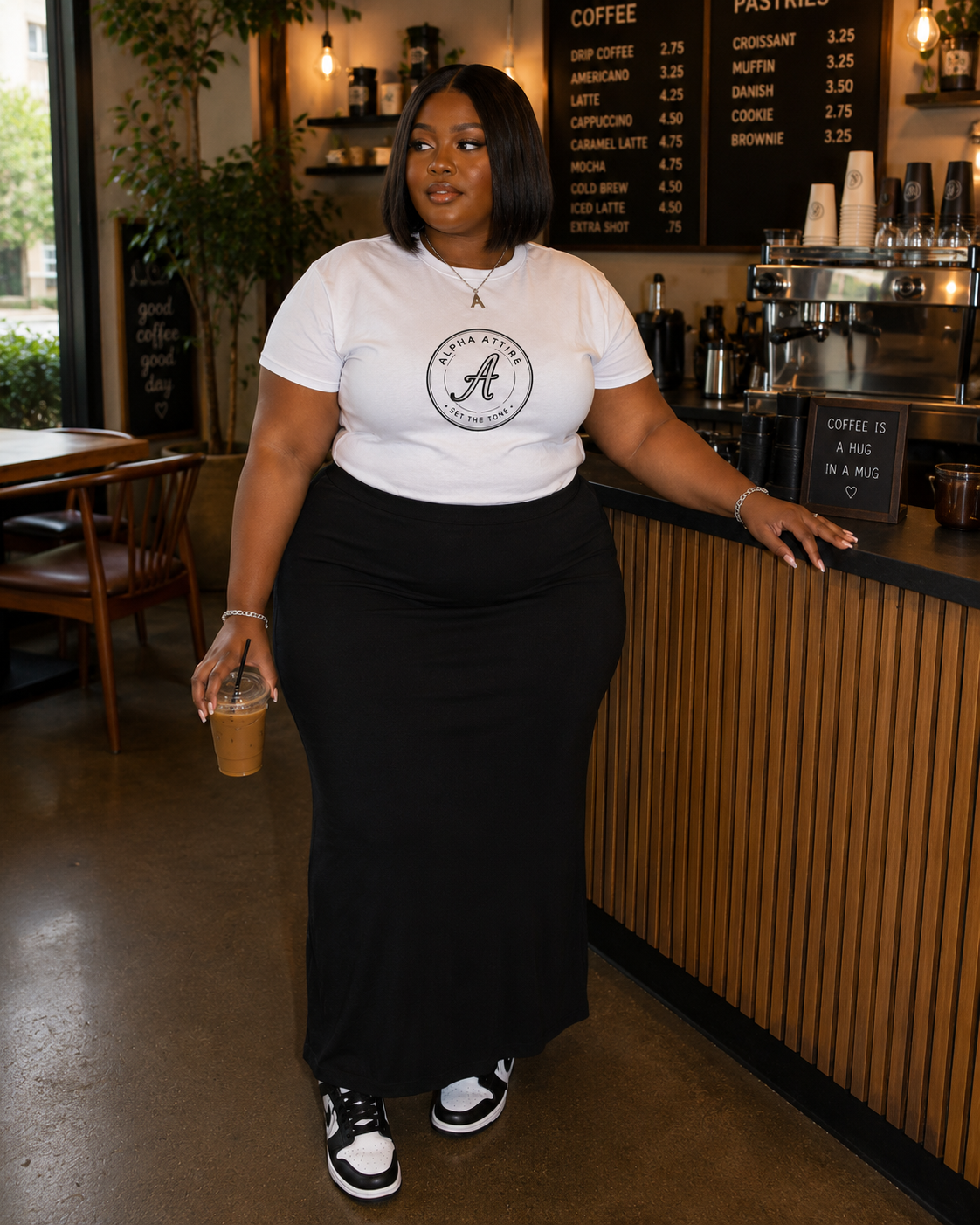 A woman wearing an Alpha Attire graphic tee in a coffee shop