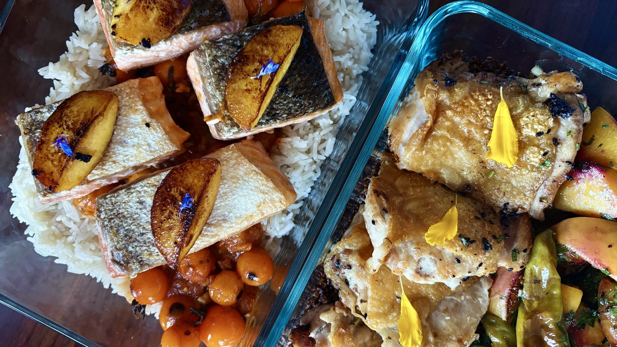 Multiple glass containers filled with salmon, chicken, heirloom tomatoes