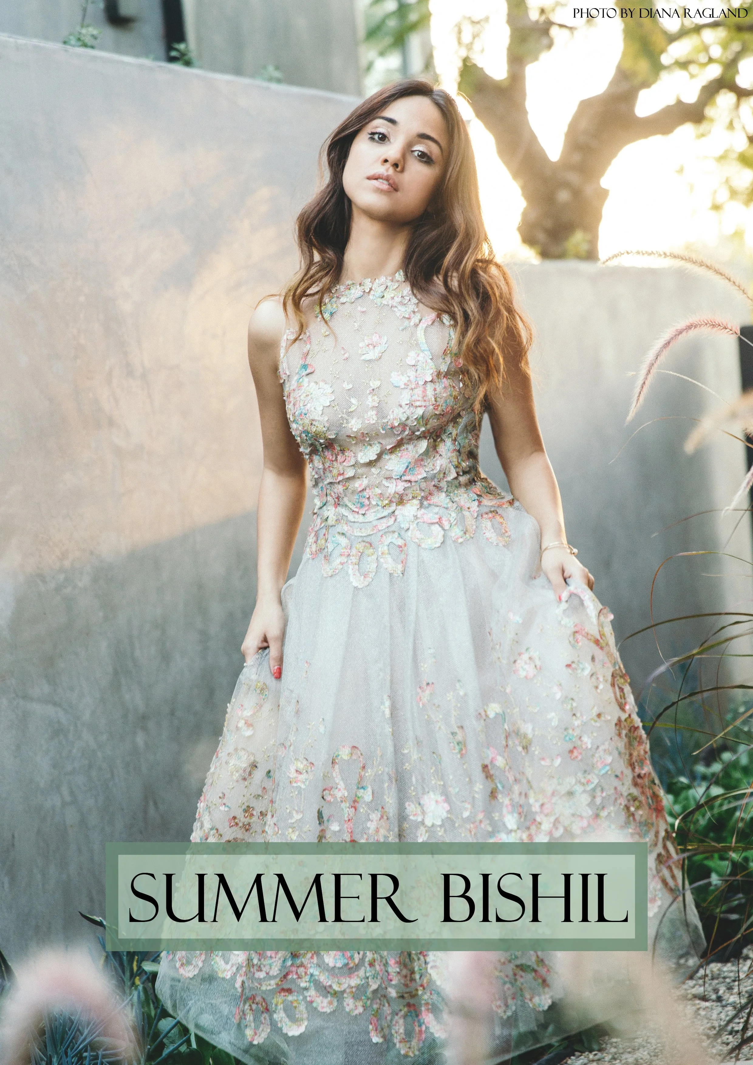 A young woman in a floral embroidered dress standing outdoors with sunlight behind her, with the hashtag #SUMMERBISH on the image.