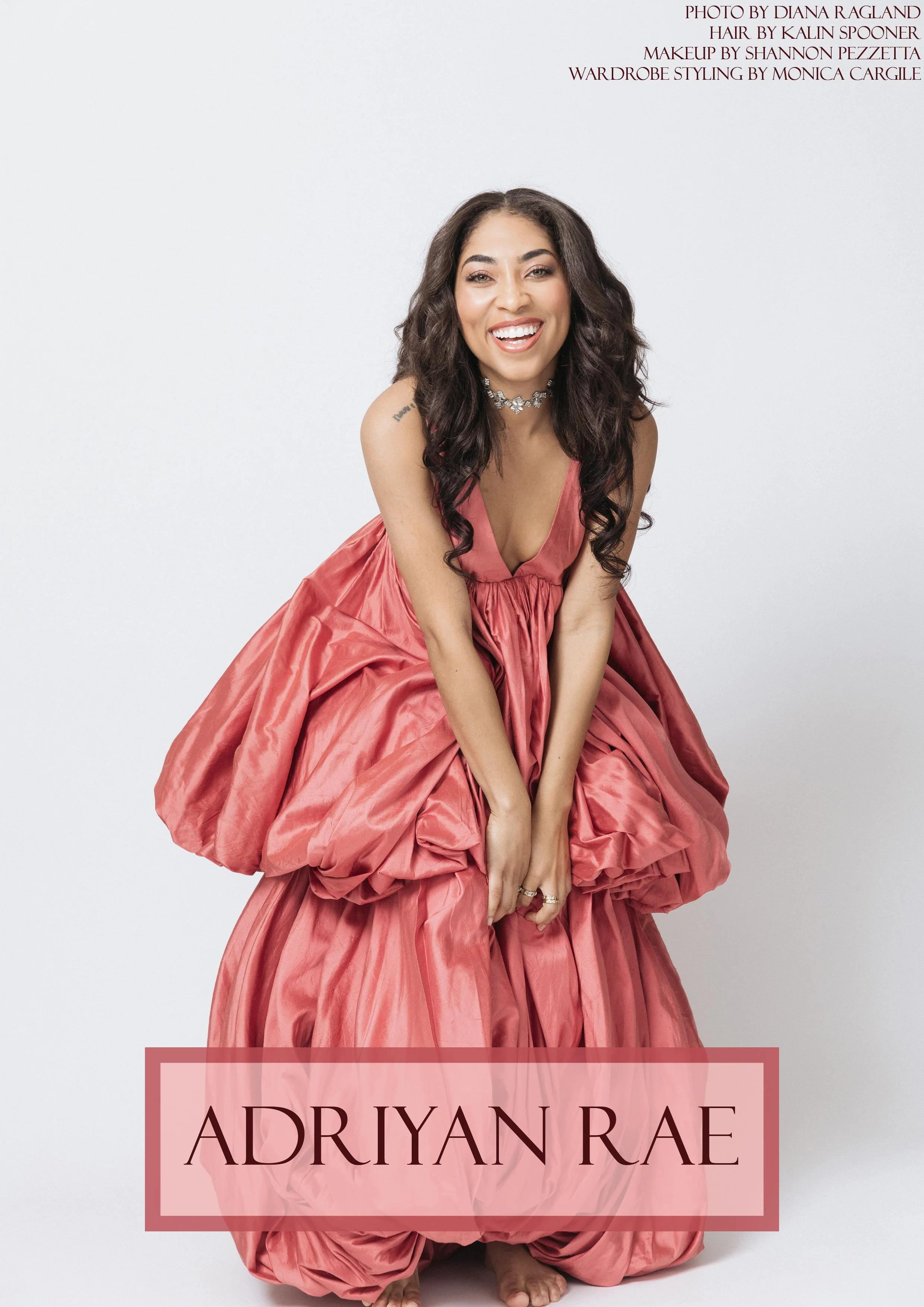 Portrait of a woman in a pink ball gown, smiling, with long dark curly hair, against a white background.