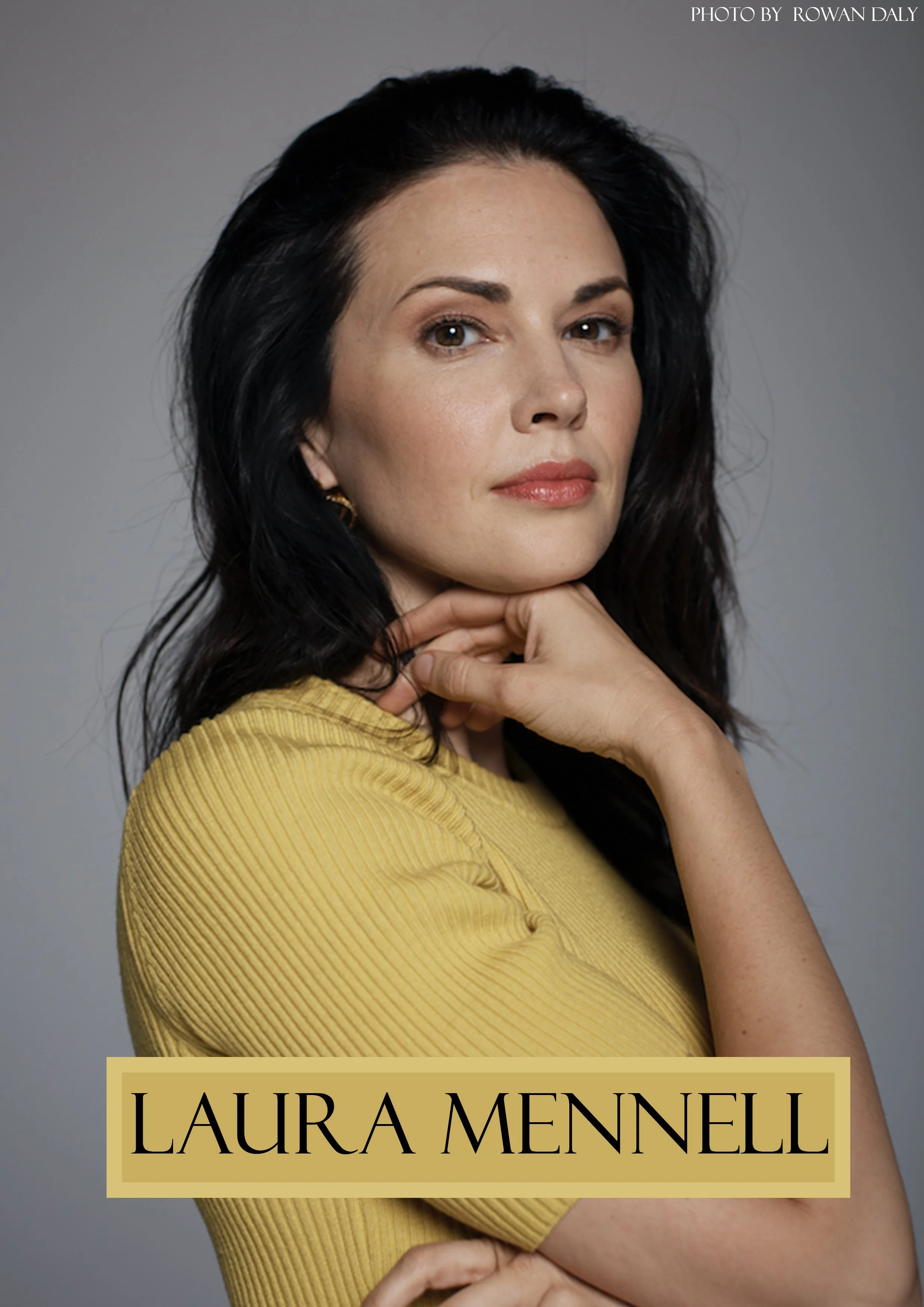 Portrait of a woman with dark hair, wearing a yellow ribbed top, standing against a grey background, with text reading 'LAURA MENNELI' at the bottom and a photo credit to Rowan Daly at the top right.