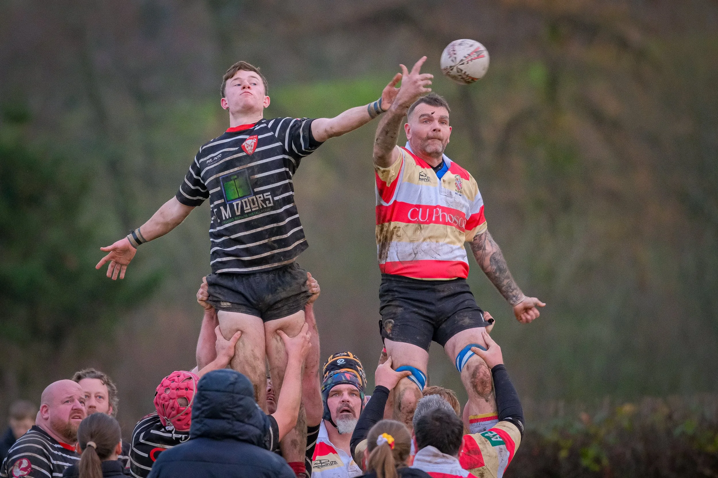 Rugby players performing a lineout during a match, with players lifting their teammates to catch the ball.