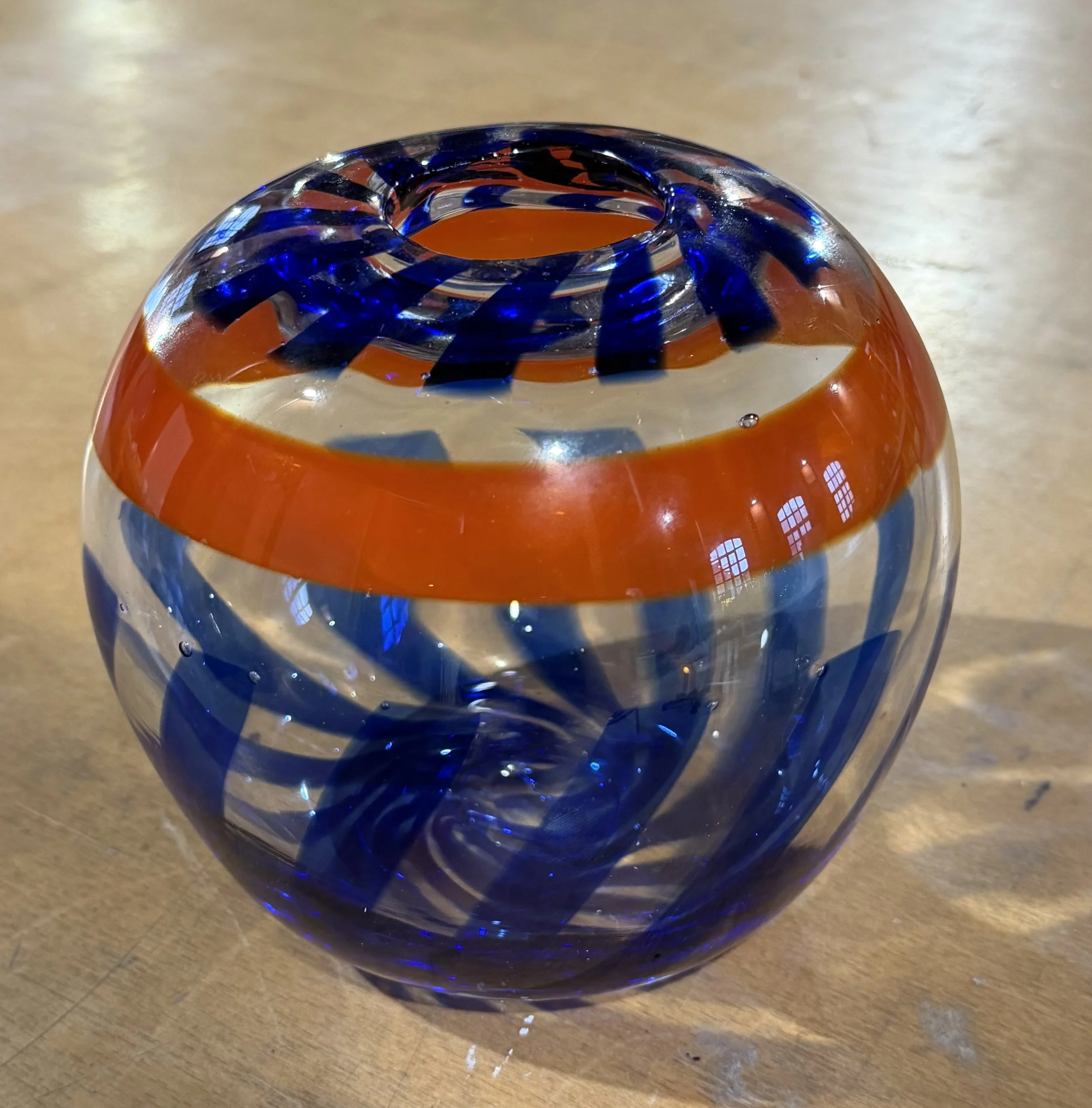 Handblown glass vase: Clear globe with orange band and blue stripes.