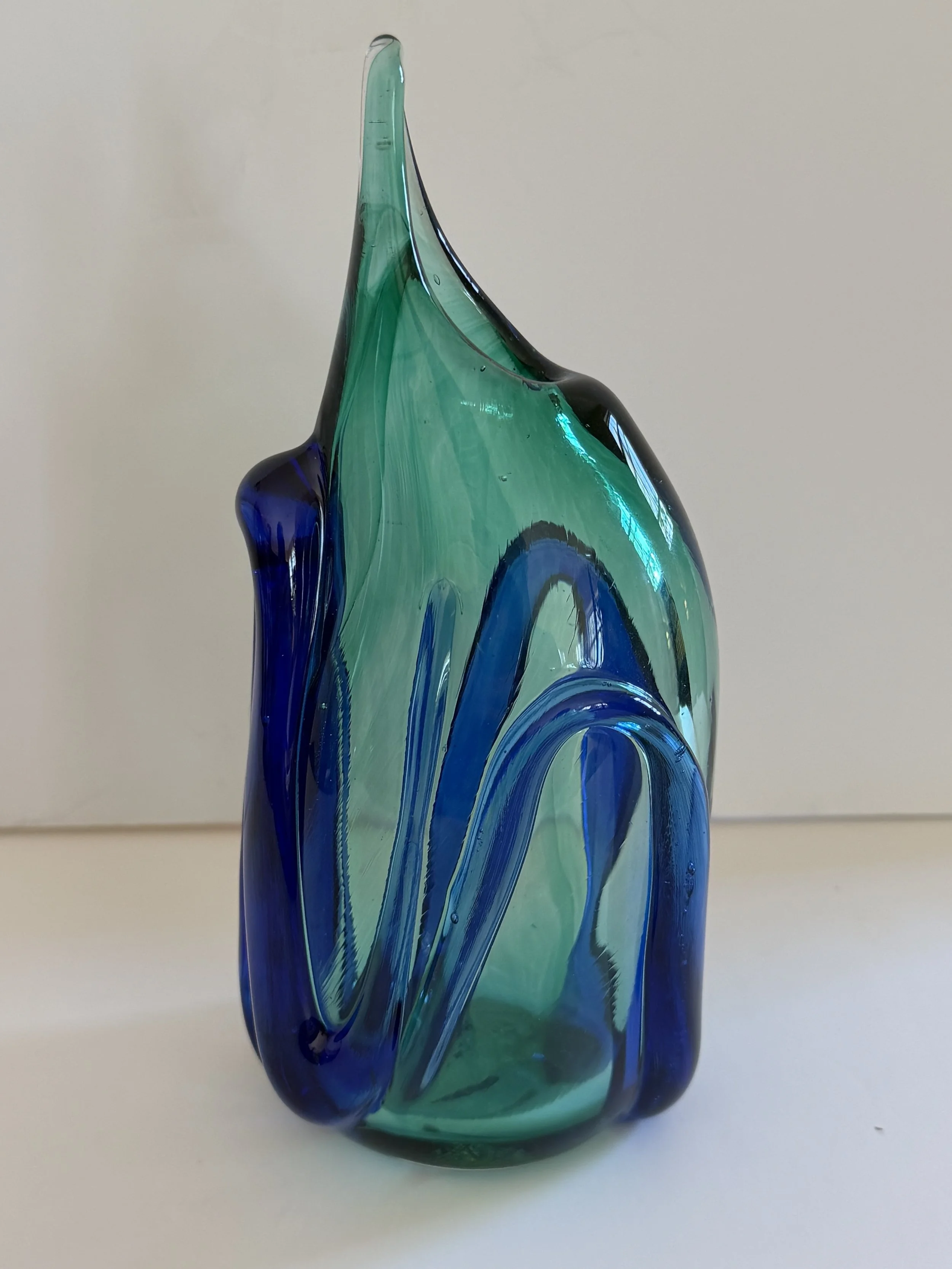 Handblown glass vase: Pointed transparent green with raised dark blue ribbons.