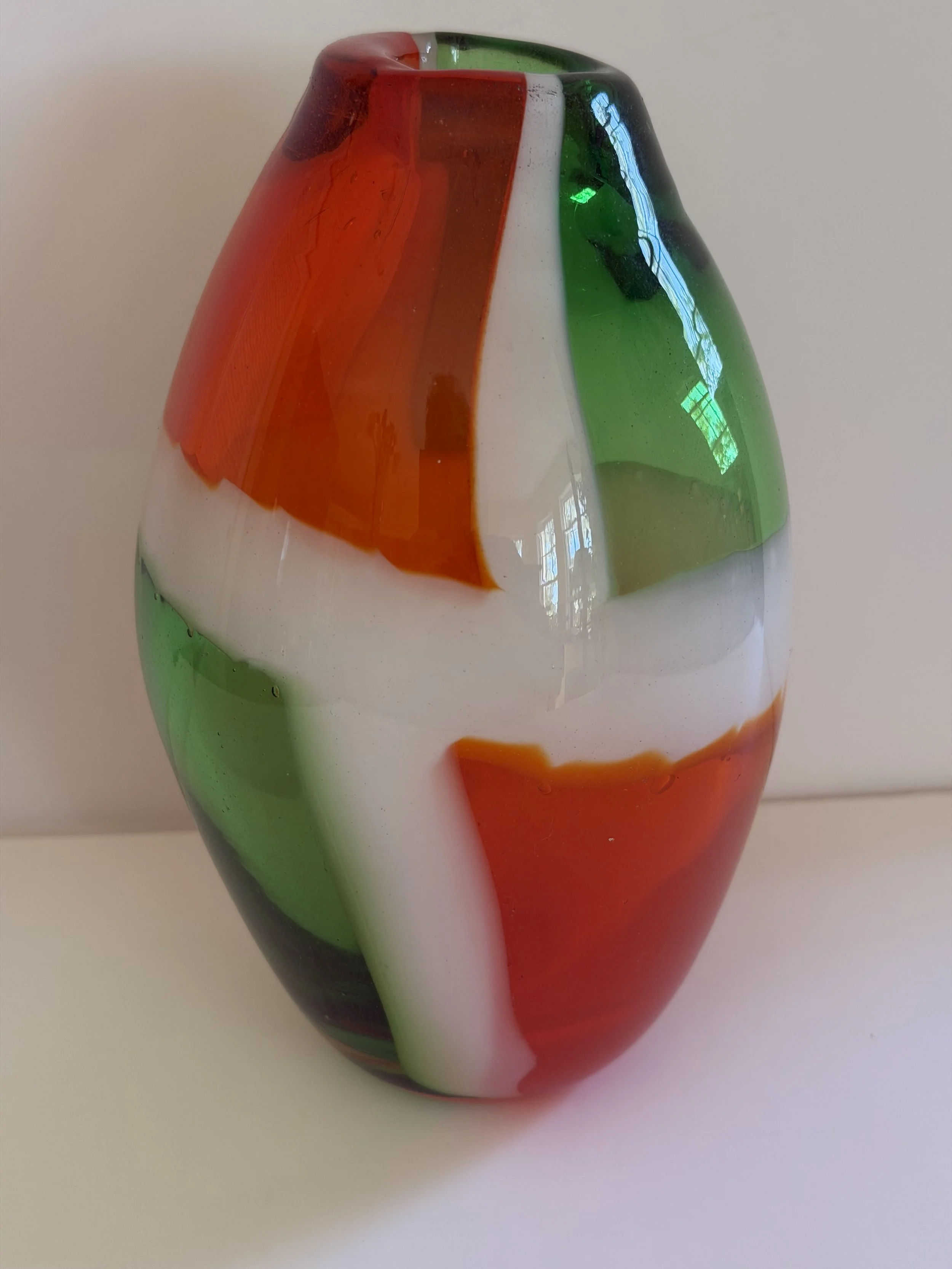 Handblown glass vase: Transparent orange and green with white borders.