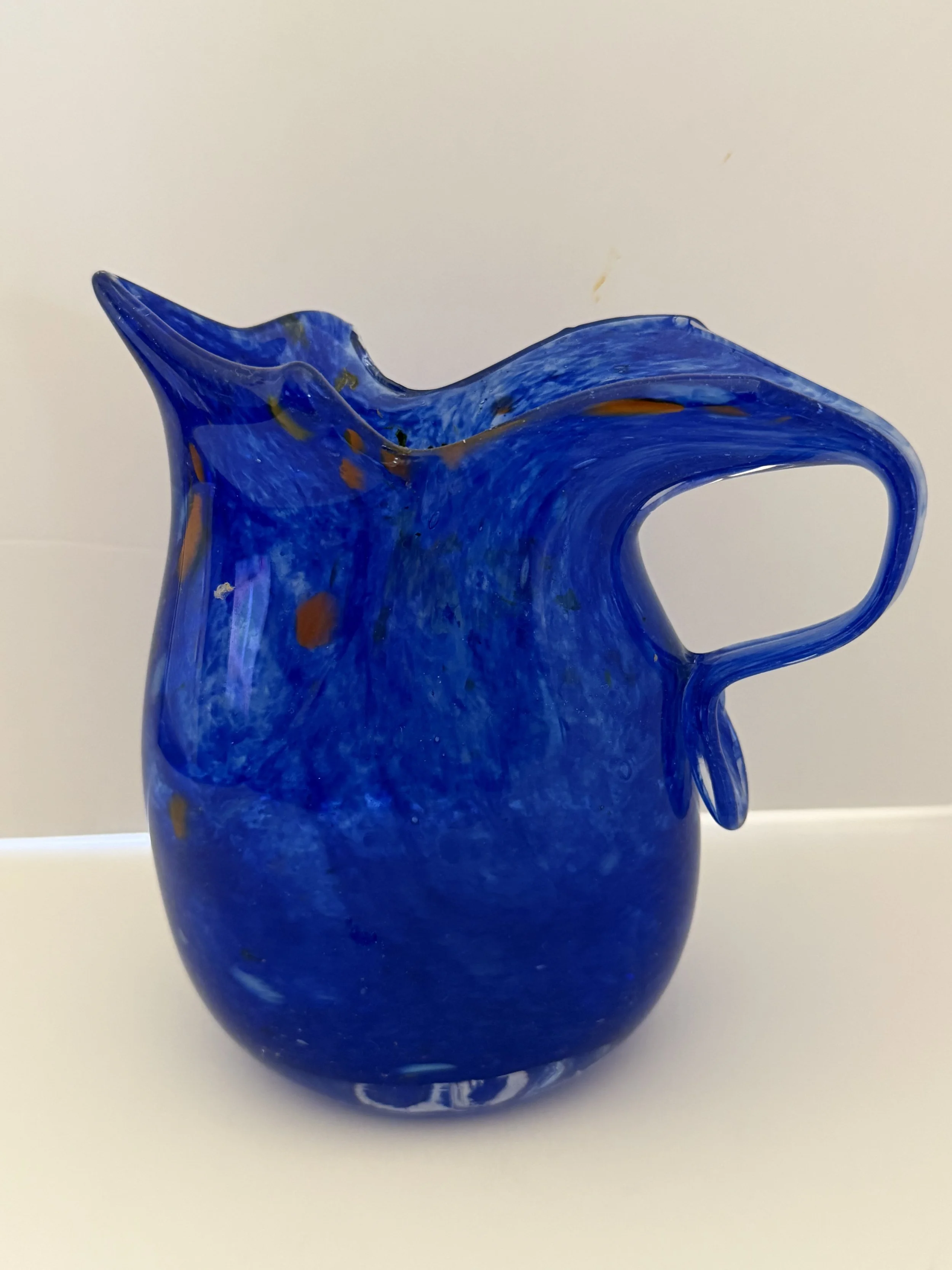 Handblown glass pitcher: Cobalt blue pitcher with multicolored accents.