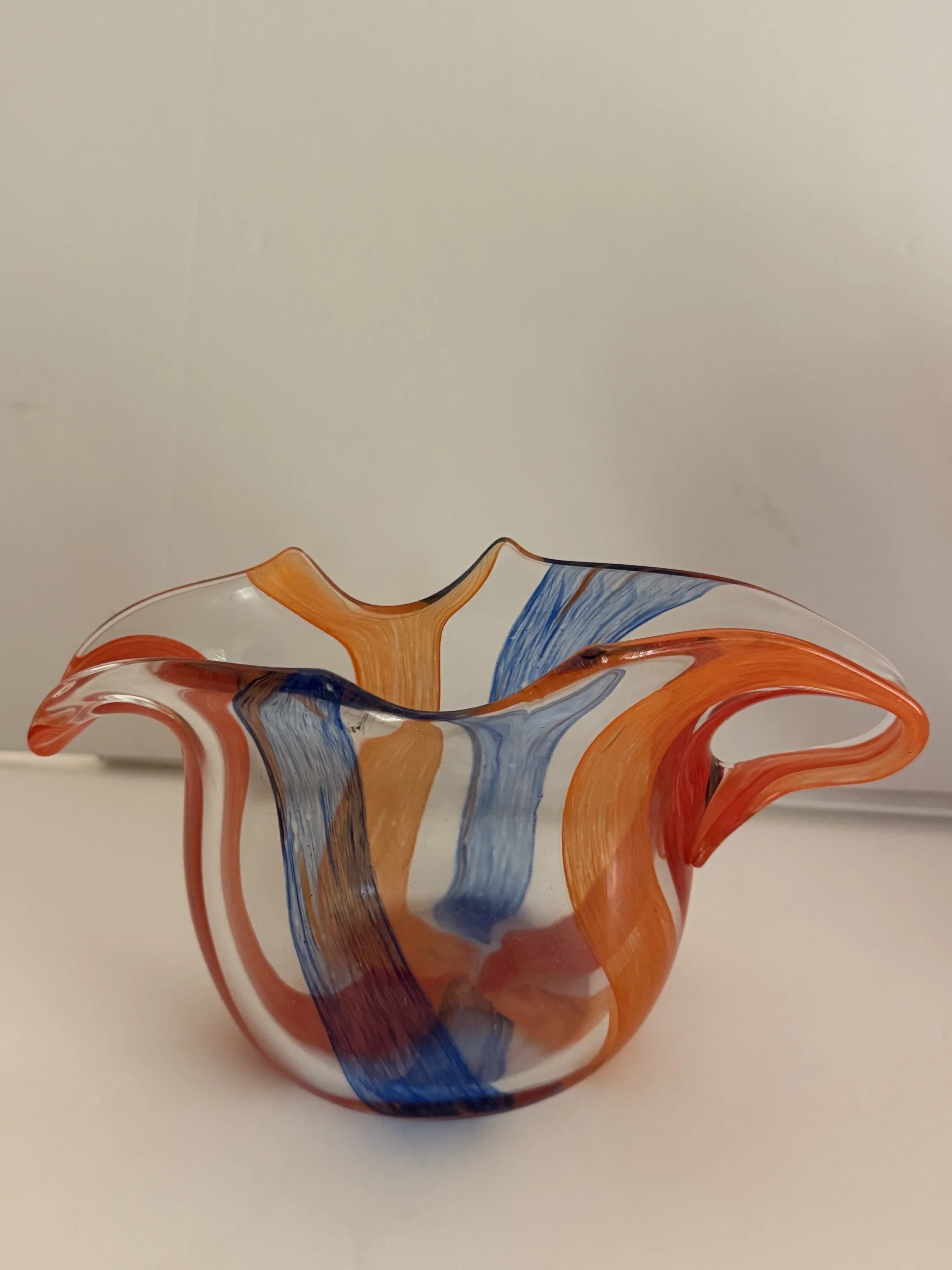 Handblown glass pitcher: Small, clear pitcher with blue, red and orange bands.