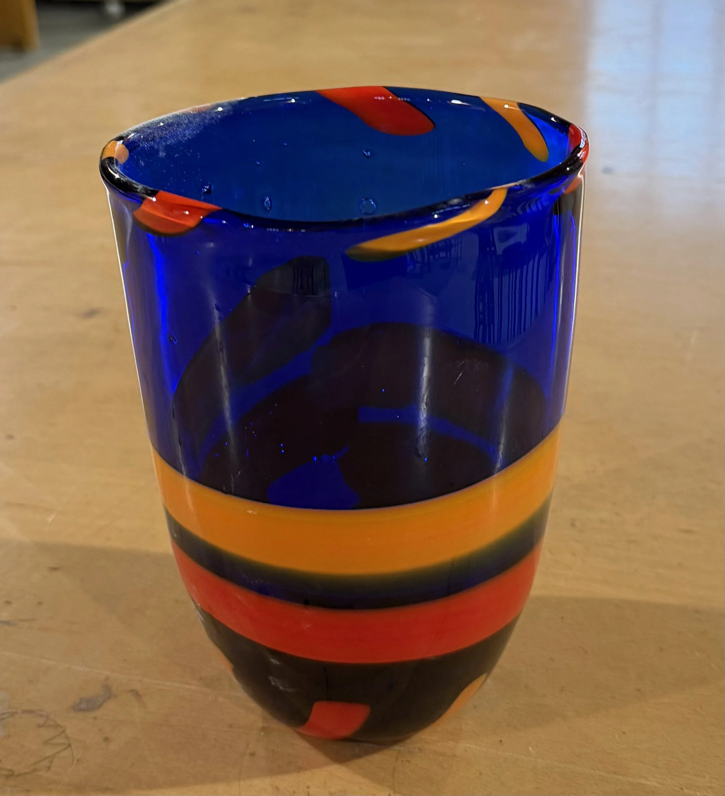 Handblown glass vase: Wide-mouthed blue vase with orange and red bands.