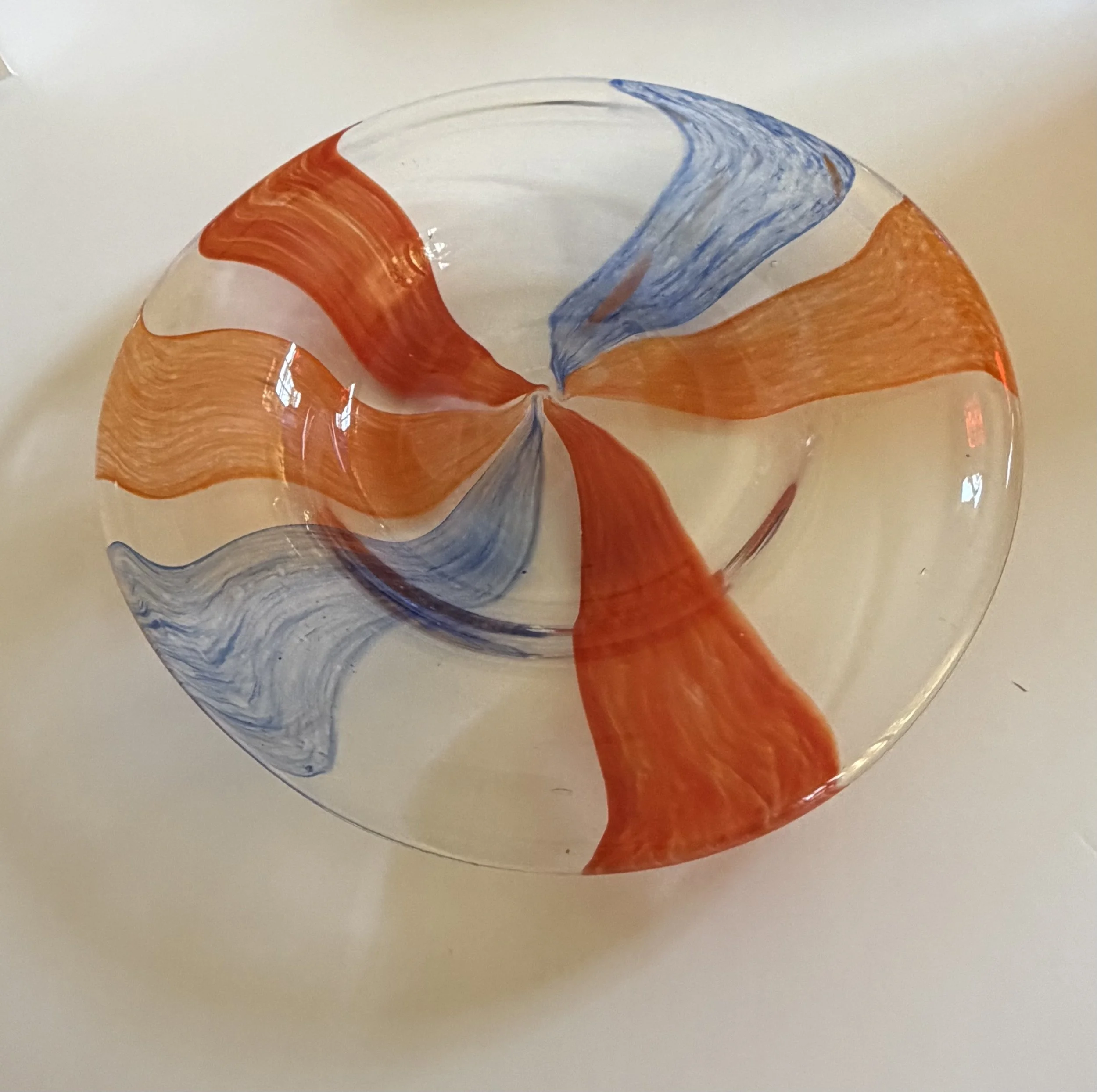 Handblown glass plate: Clear plate with orange, red and blue stripes.