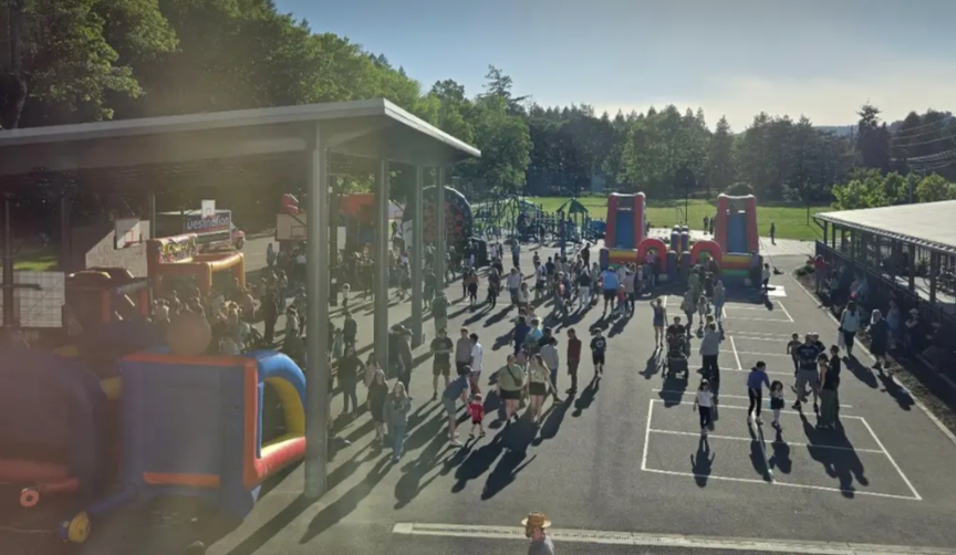 A busy outdoor playground and event area with children and adults, featuring inflatable bounce houses, climbing structures, and a basketball court.