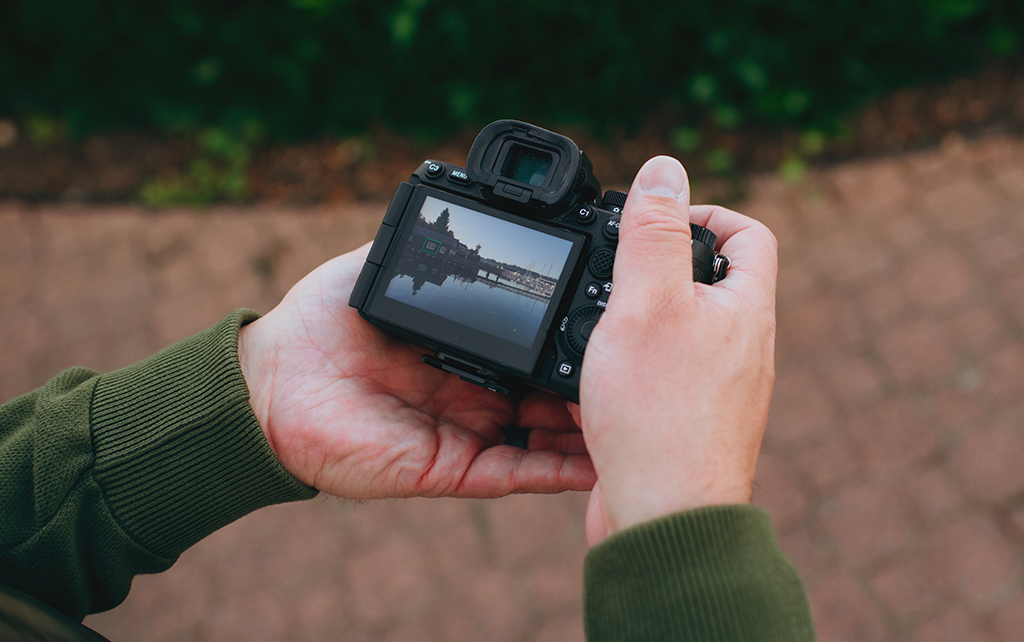 Glen German holds a camera reviewing a recently taken picture of the harbor