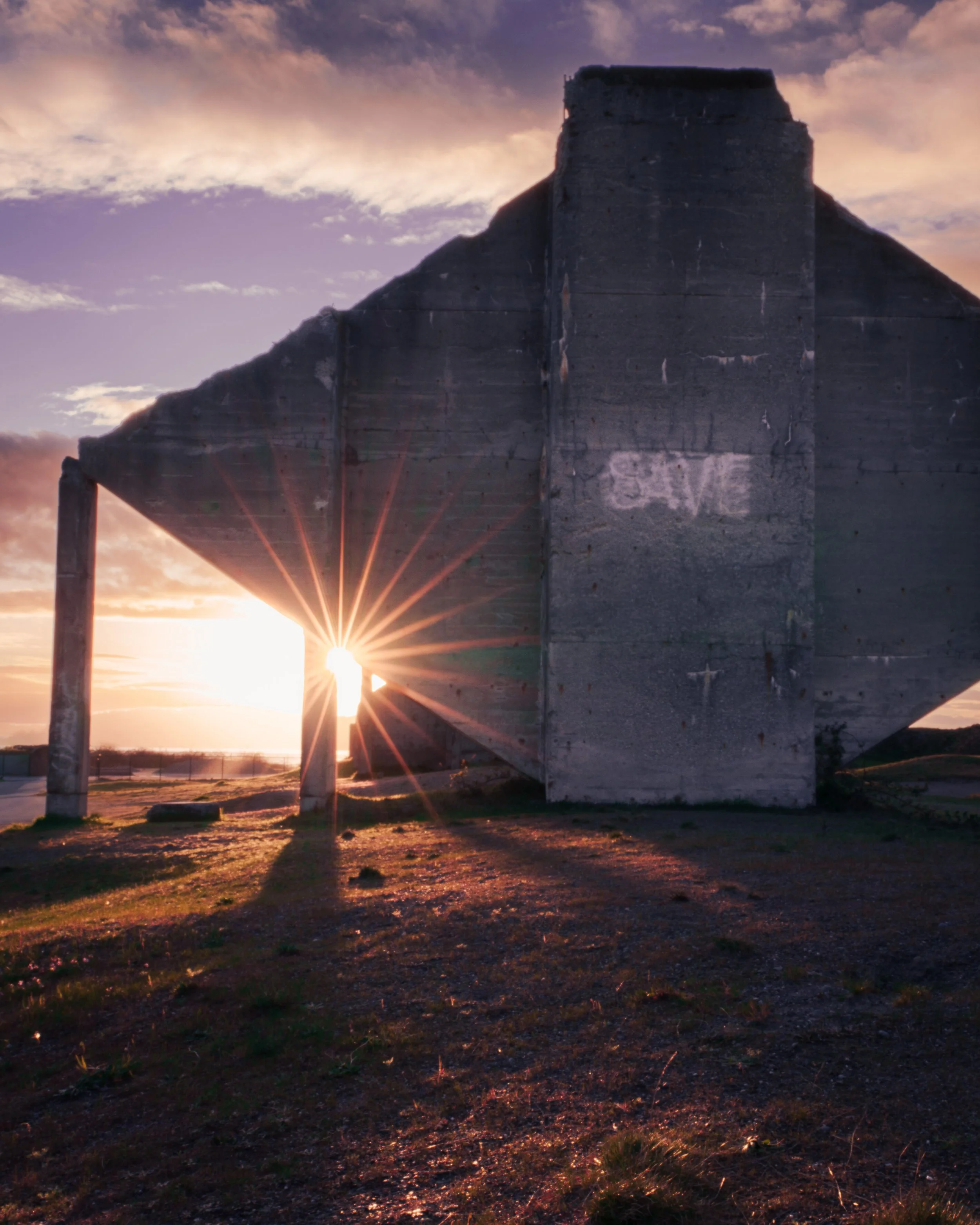 Ancient stone pyramid with sunrise in the background, open field in foreground.