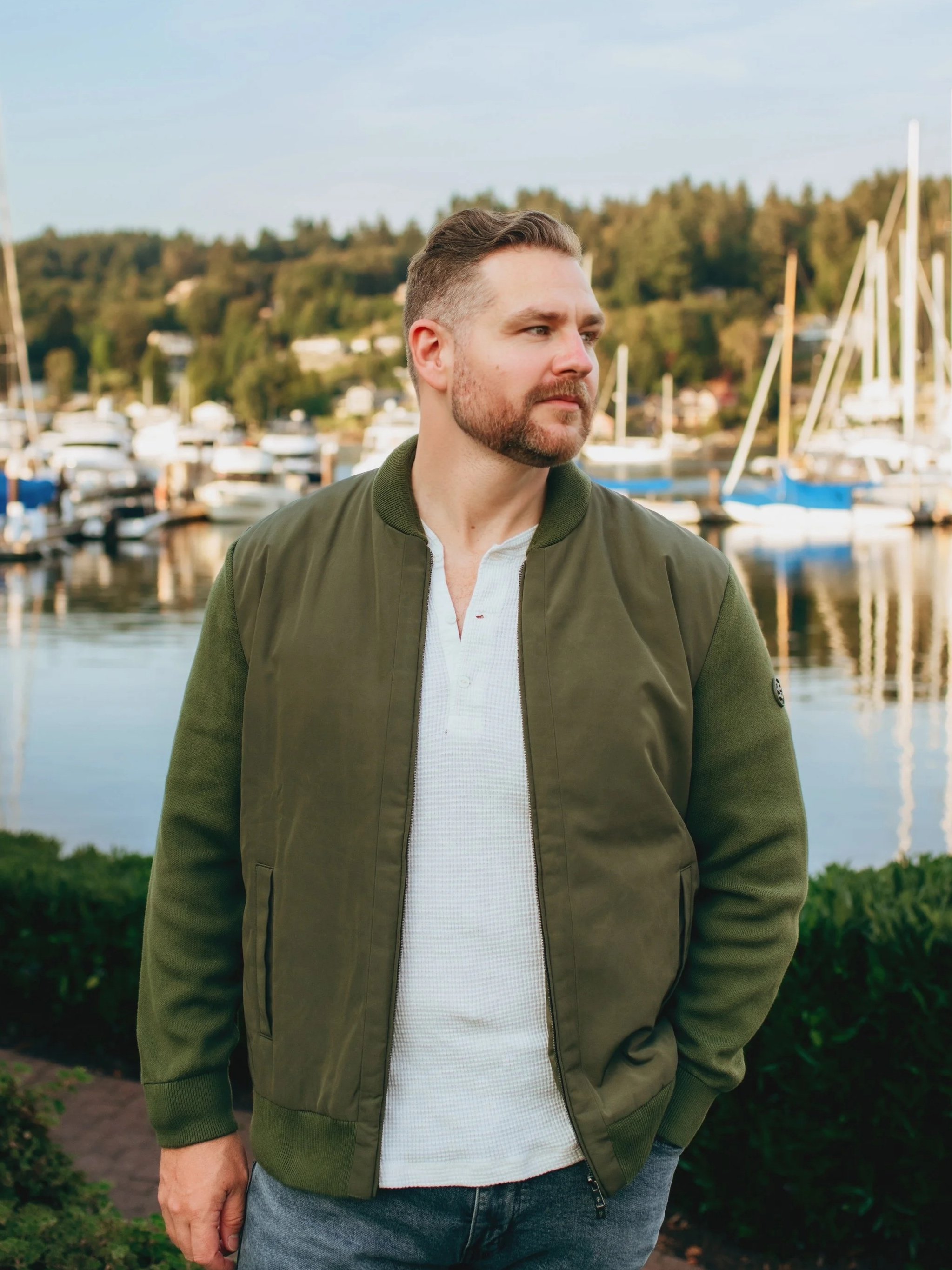 Glen German Pacific Northwest photographer stands against a harbor filled with sailboats in Gig Harbor Washington.
