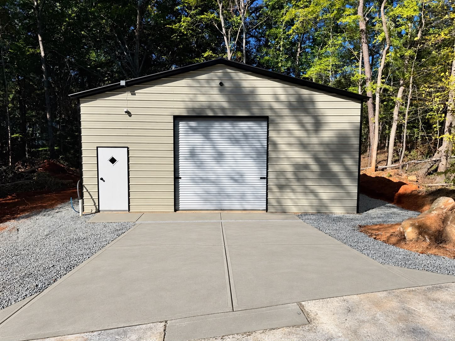Concrete driveway extension to a metal garage Metal garage with bare clay before the concrete approach Gravel base and forms set before the concrete pour