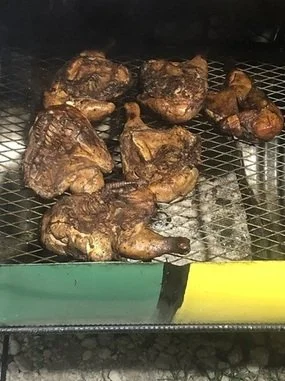 Six grilled T-bone steaks cooking on a wire rack over heat.