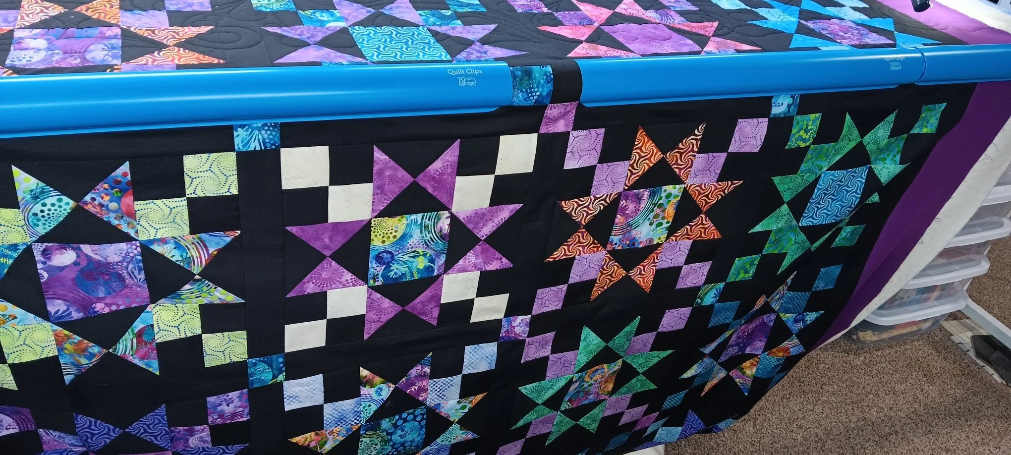 Black cosmic quilt on the quilt table.jpeg