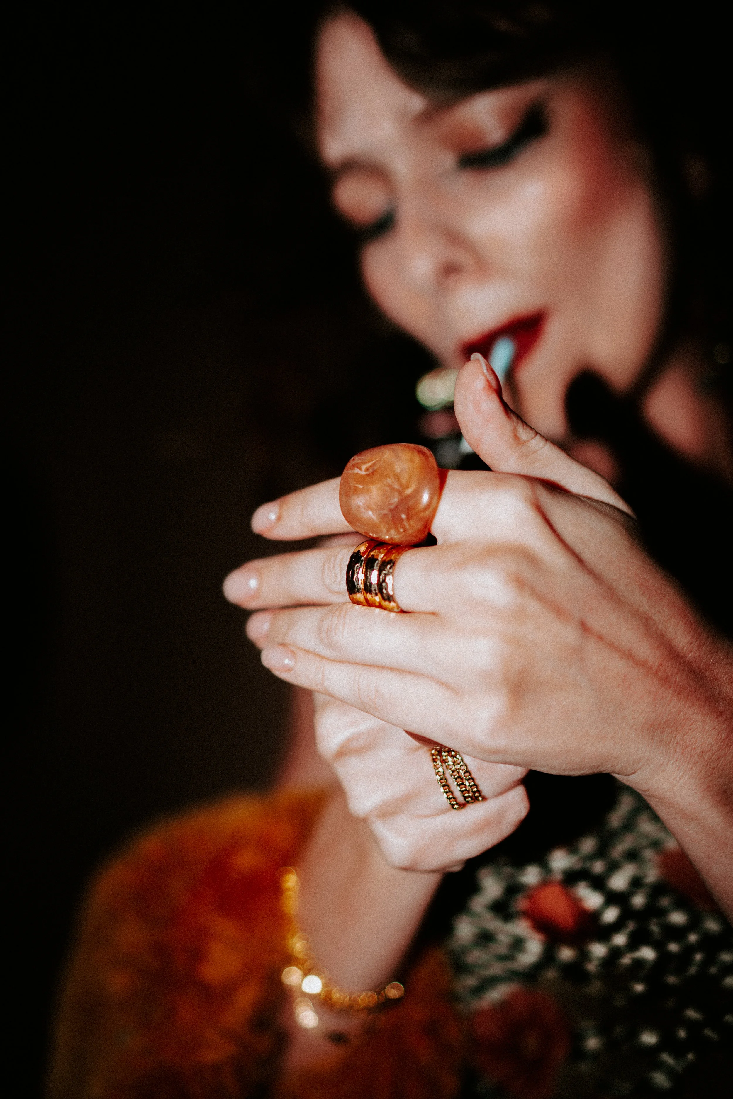 A woman with makeup and rings is holding a cigarette or joint close to her mouth.