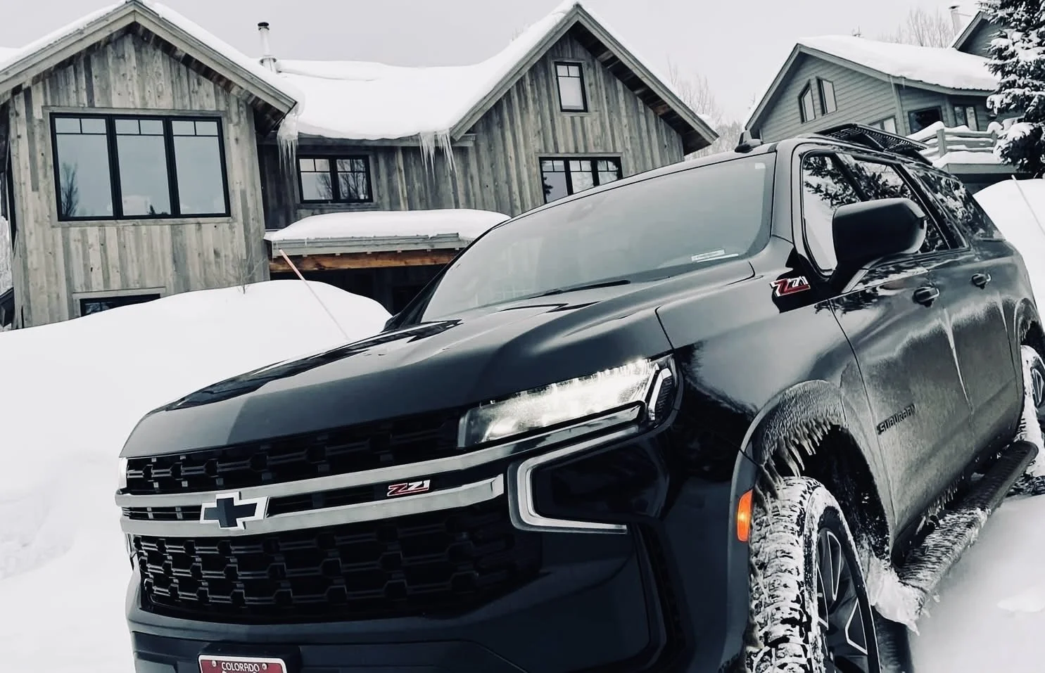 Luxury black Suburban parked in front of a snowy house in Telluride, CO