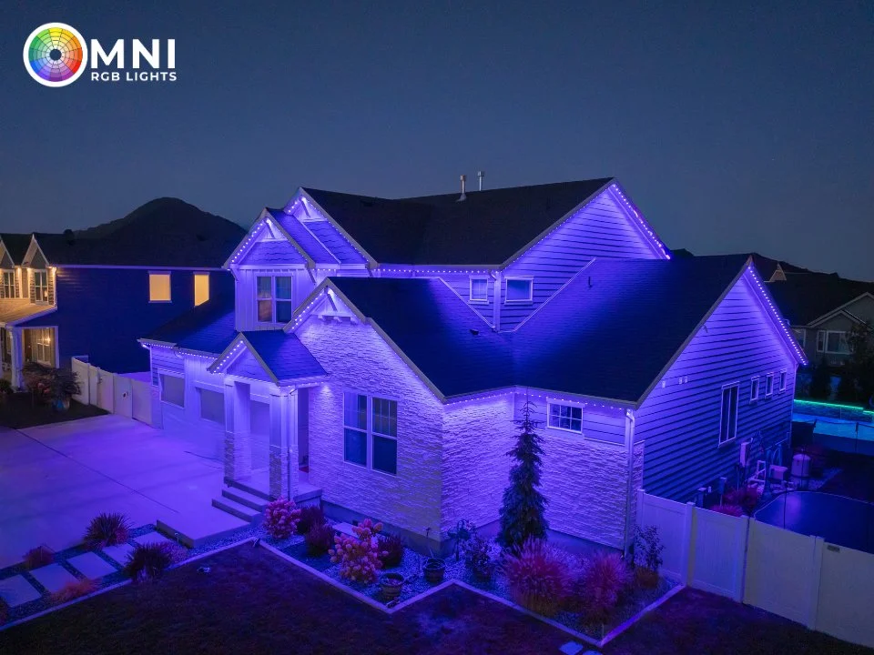 Large suburban home illuminated with purple-blue RGB LED roofline lights at dusk