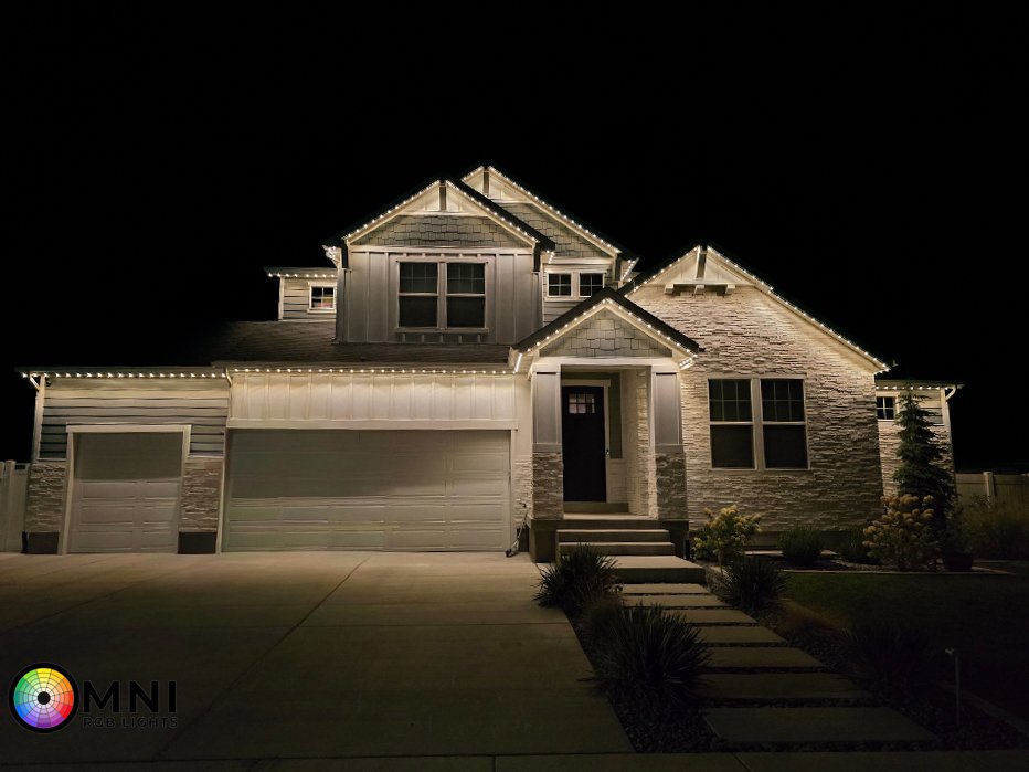Modern suburban house illuminated with warm white roofline lights at night