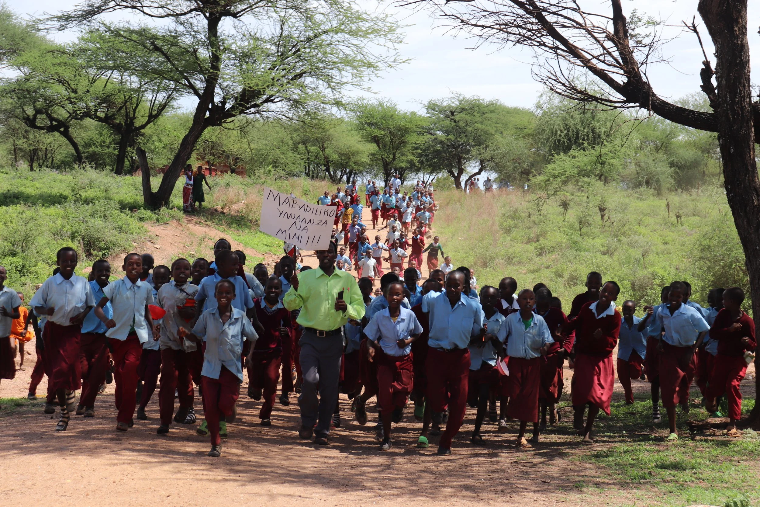 A group of students gathered outdoors beneath trees.