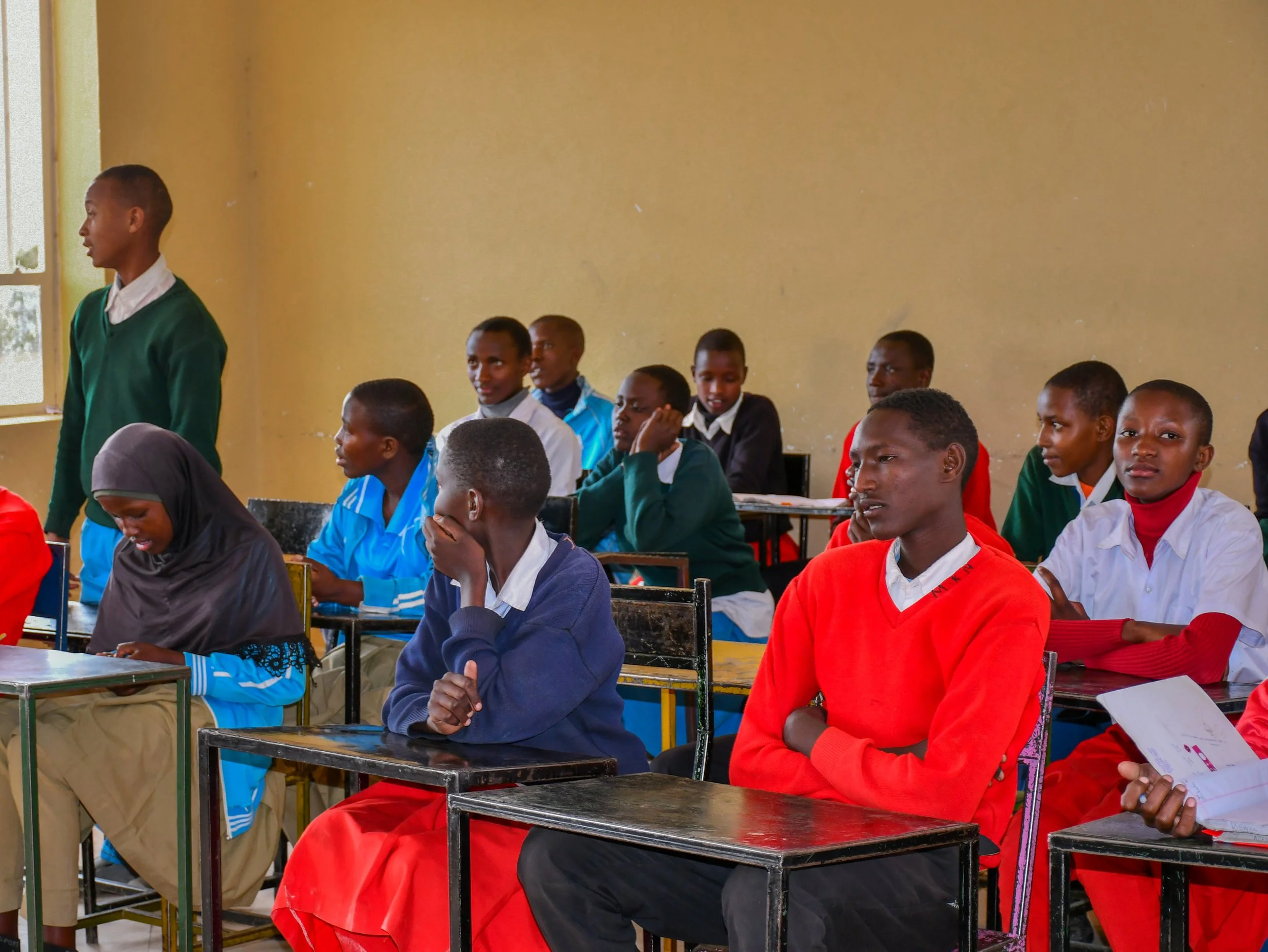 Students in colorful school uniforms gathered in a classroom.