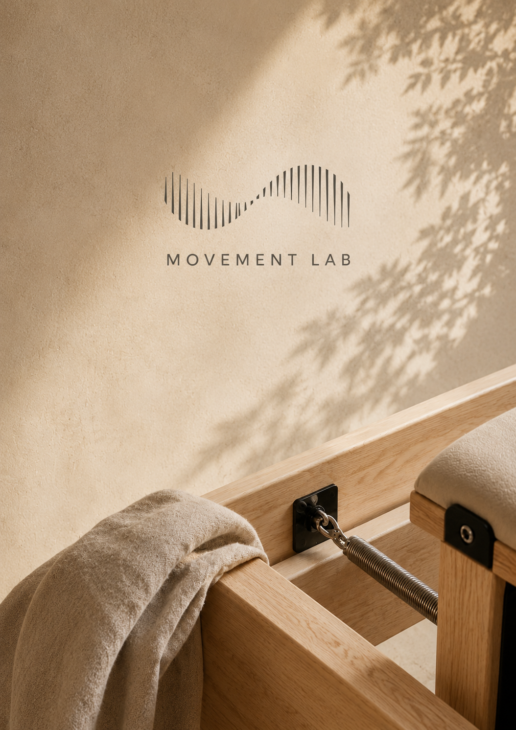 Mural en la pared con el logotipo de 'Movement Lab', un diseño de líneas curvas y rectas, con una mesa de madera y una toalla beige en primer plano, en un entorno luminoso y decorativo.