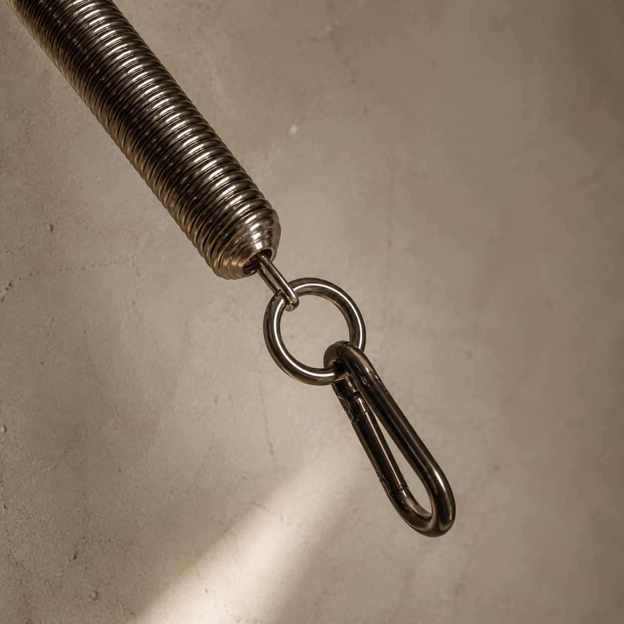 Un gancho de metal conectado a una cuerda metálica en una pared de cemento.