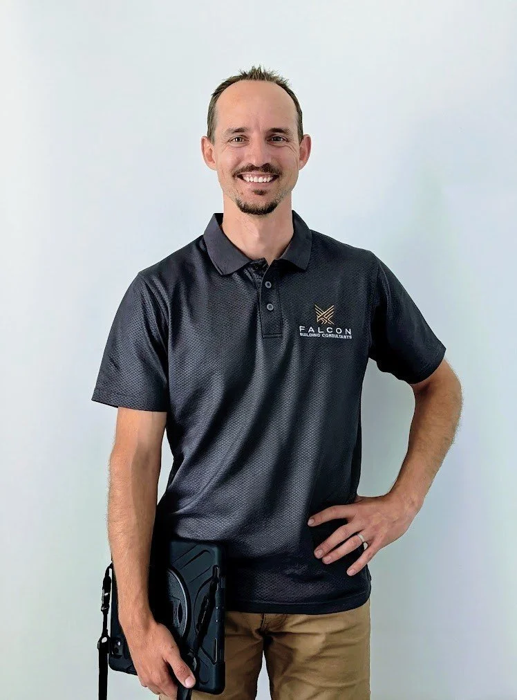 BJ Cilia - Director - Falcon Building Consultants wearing a black polo shirt with Falcon Building Consultants logo, khaki pants, and holding a tablet.