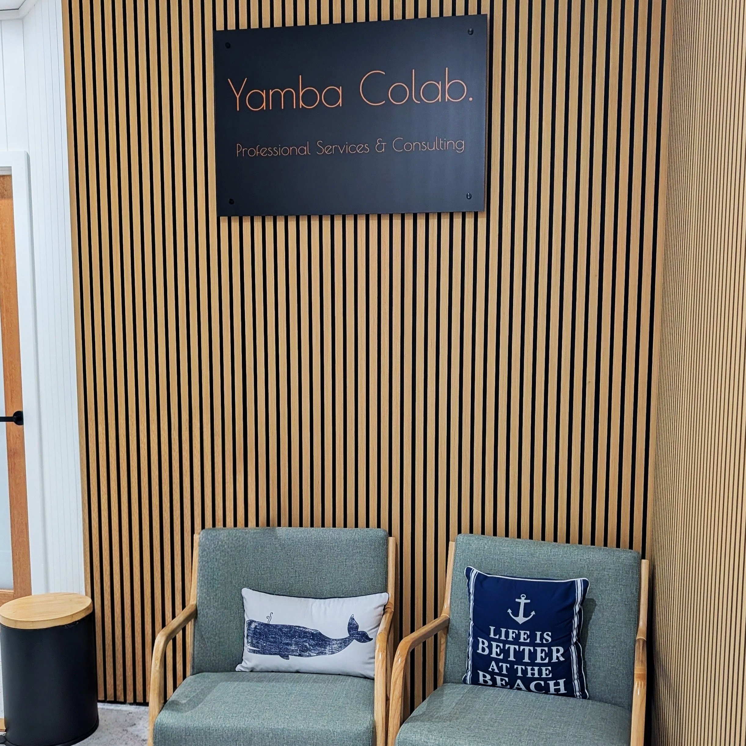 Yamba Colab entrance and reception with two chairs with cushions. Sign reads 'Yamba Colab. Professional Services & Consulting'.  A collection of office suites in the heart of Yamba CBD.