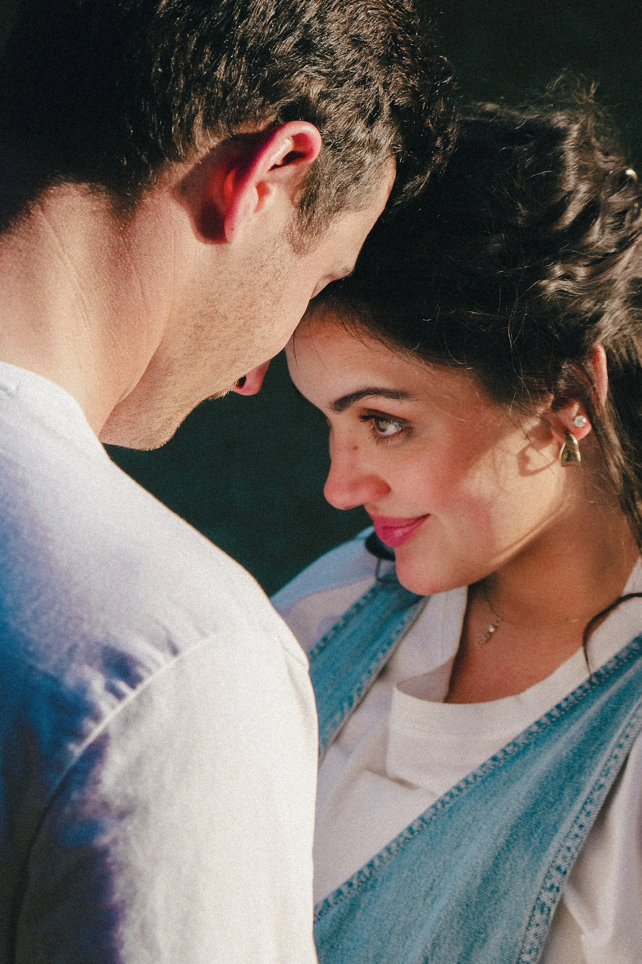 A close-up of a young man and young woman with their foreheads touching, sharing an intimate moment.