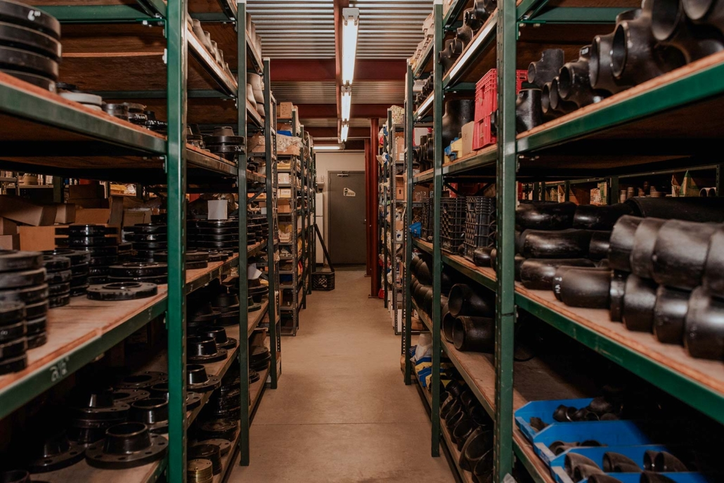 Storage room with metal shelves filled with black mechanical parts and tools.