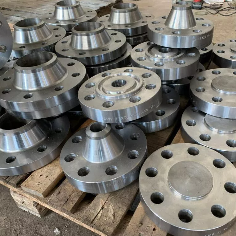 Steel flanges stacked on a wooden pallet in a workshop environment.