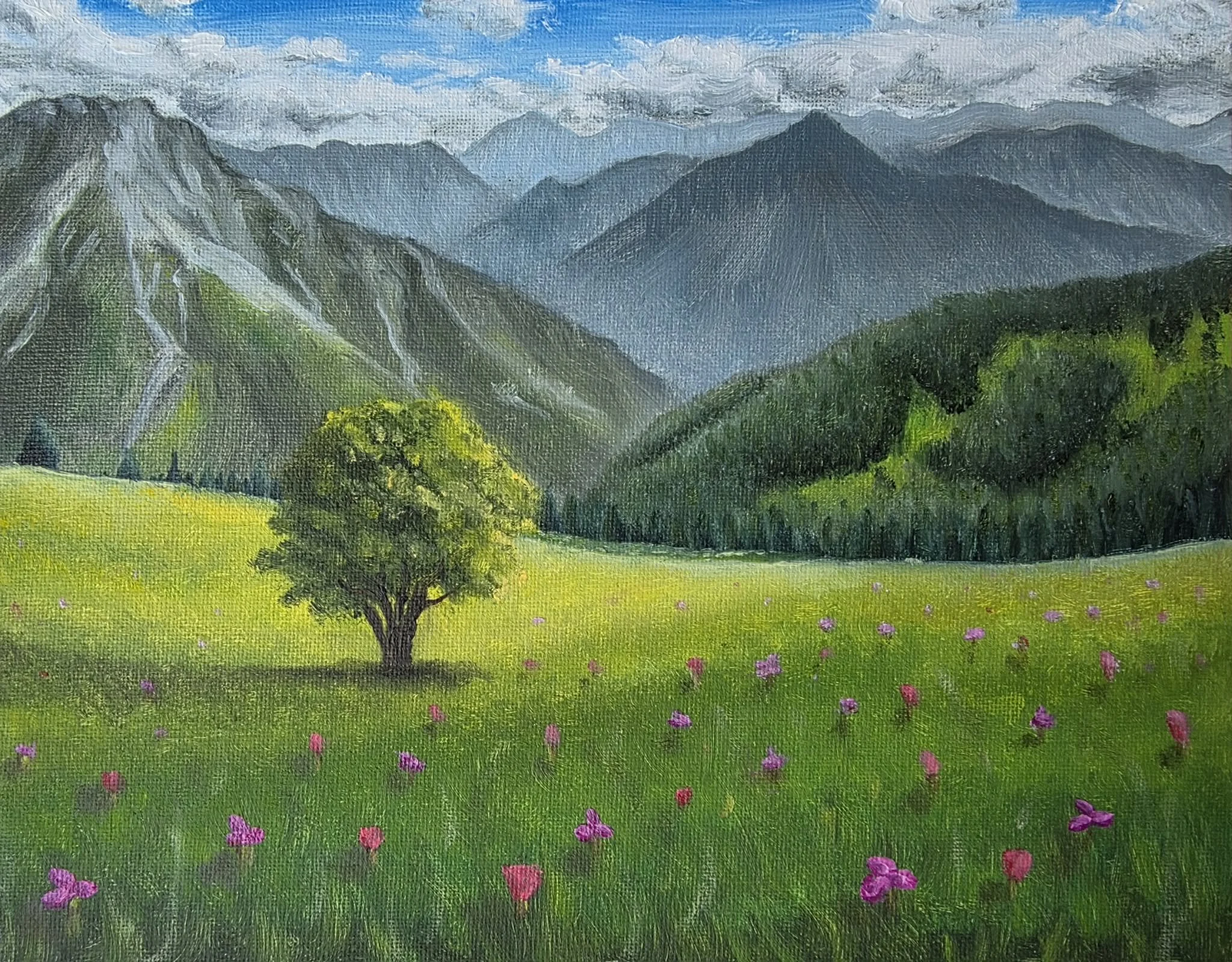 A painting of a lush green field with pink flowers, a solitary tree, and a backdrop of blue mountains under a partly cloudy sky.